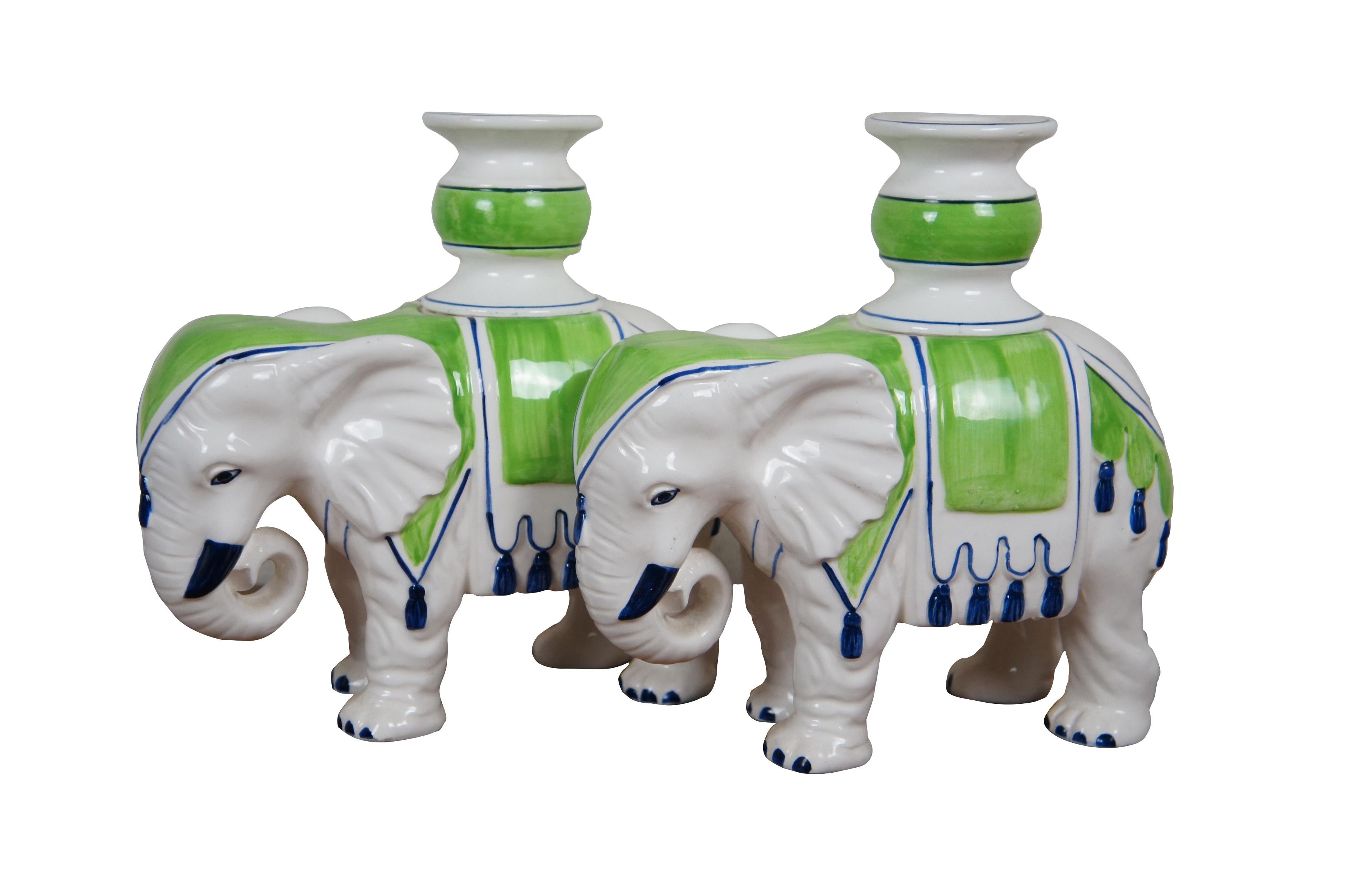 Circa 1970's Fitz & Floyd chinoiserie style white porcelain single taper candlestick holders in the shape of Indian elephants with curled trunks, draped in lime green saddlecloths with cobalt blue trim / details. Made in Japan.

