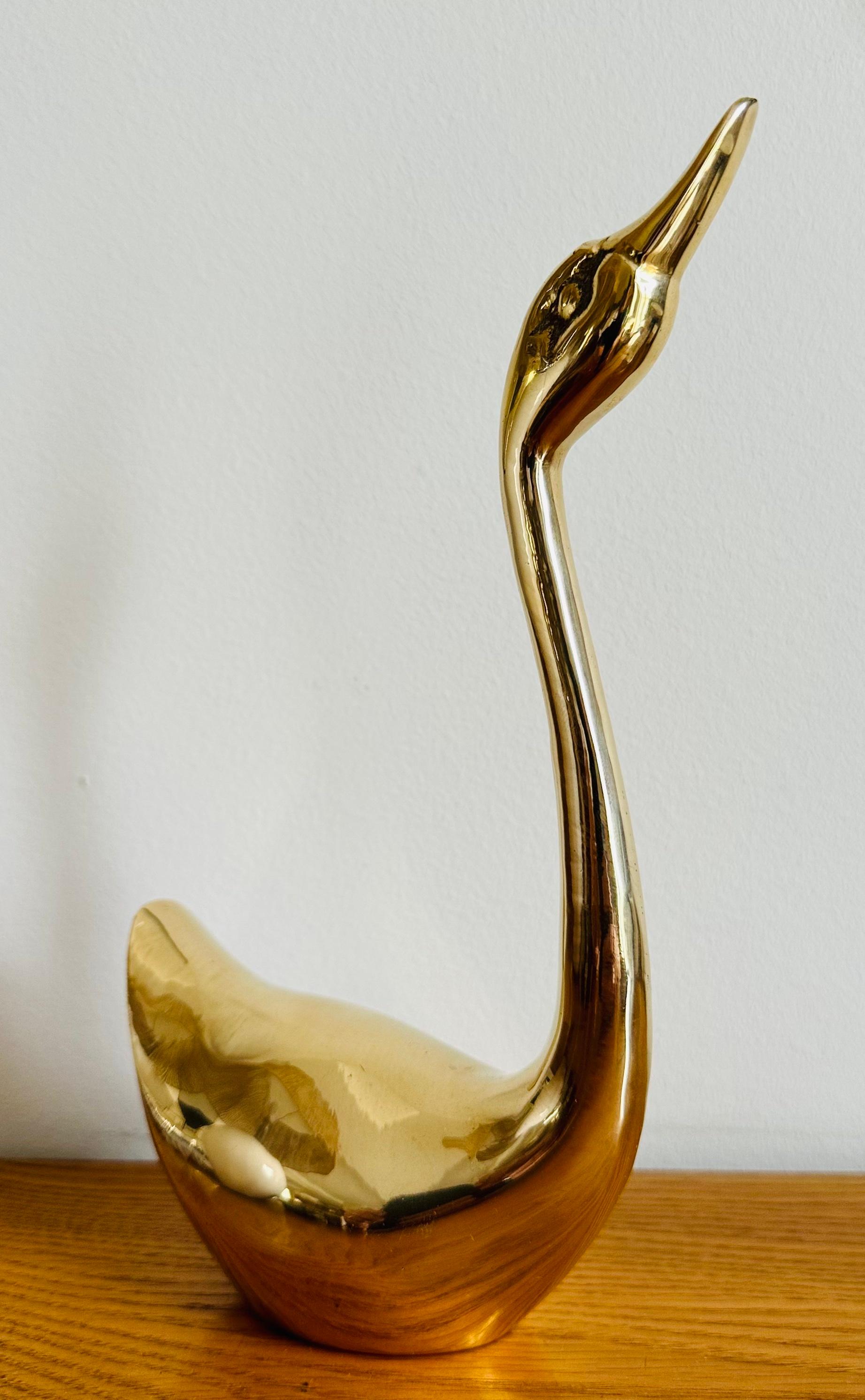 An elegant large vintage French 1970s decorative polished brass swan. In good vintage condition with a lovely patina. The swan has a couple of scratches which I've illustrated in the images. A small hole is in the base showing it's actually hollow