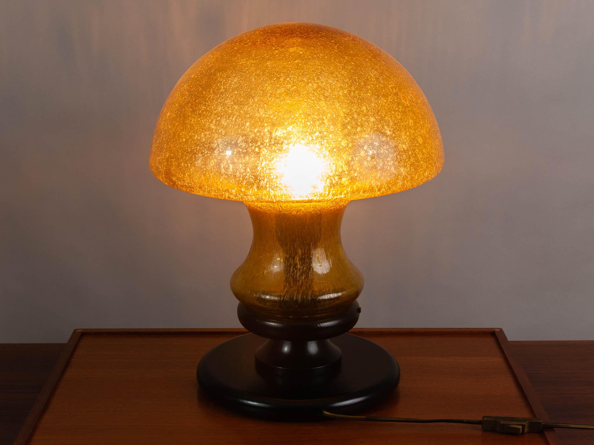Vintage 1970s German mushroom table lamp by Doria Leuchten. The hand blown, dark-amber, bubbled glass, mushroom domed shade, sits on a black wooden base. The base and the shade are held in place with three screws which are easily released to allow