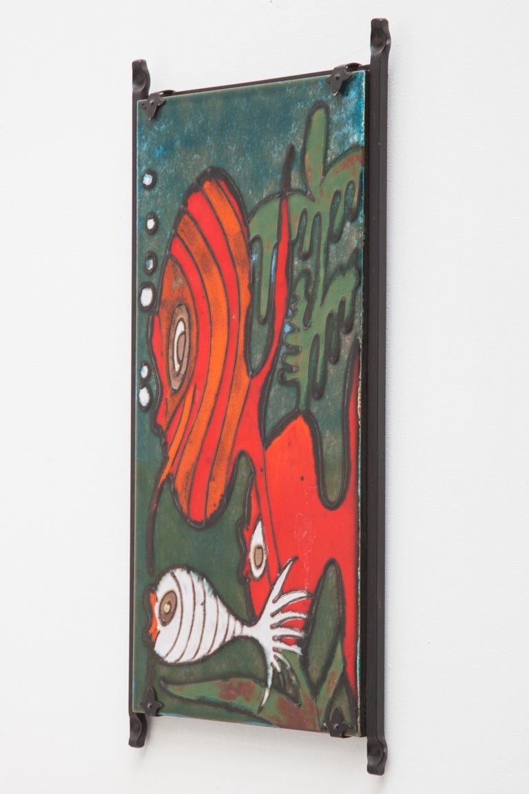 1970s West Germany wall piece by Heibi Keramik. Features a bright glossy multi-color glazes design of three fish and algae on a tile in a wrought iron frame. Still bears the original label.