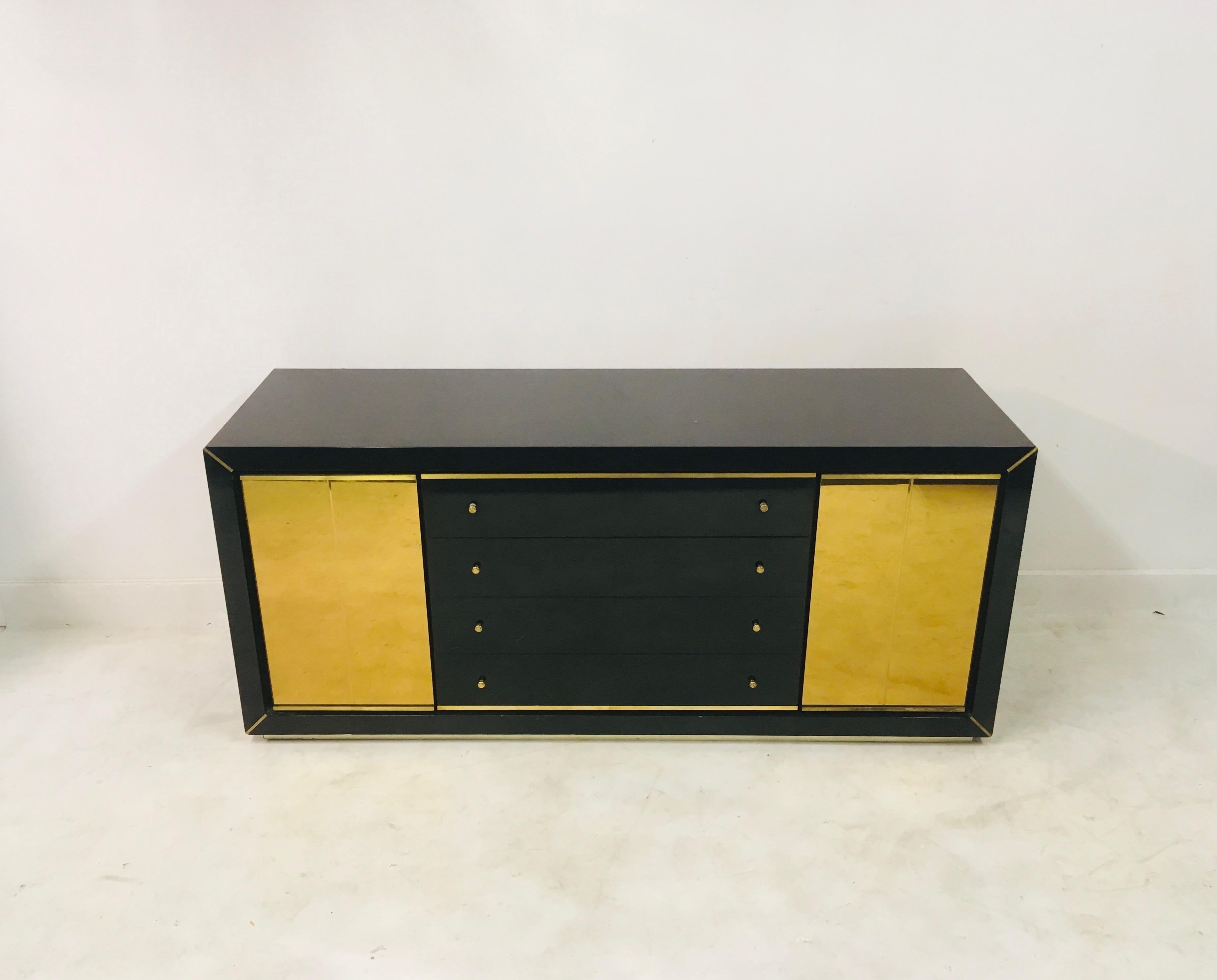 Black lacquered sideboard

Brass handles

Brass base and corner detail

Two gold glass doors

Four drawers

Italy, 1970s.