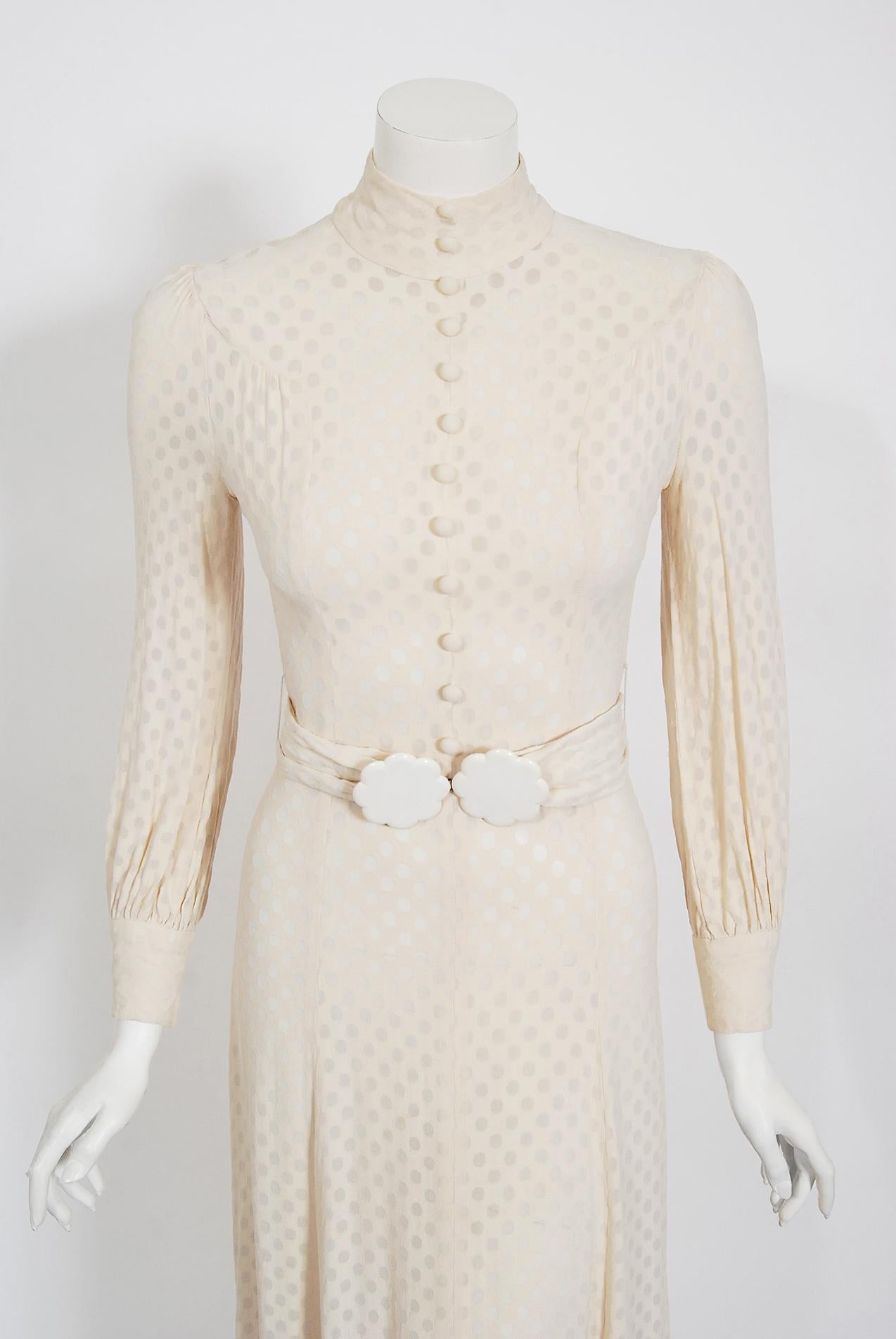 A stunning Wallis of London ivory semi-sheer dotted crepe dress, dating back to the early 1970's. The bodice has the chicest high-neck with tailored pleat work to create flattering curves. I love the front covered buttons which are also mirrored on
