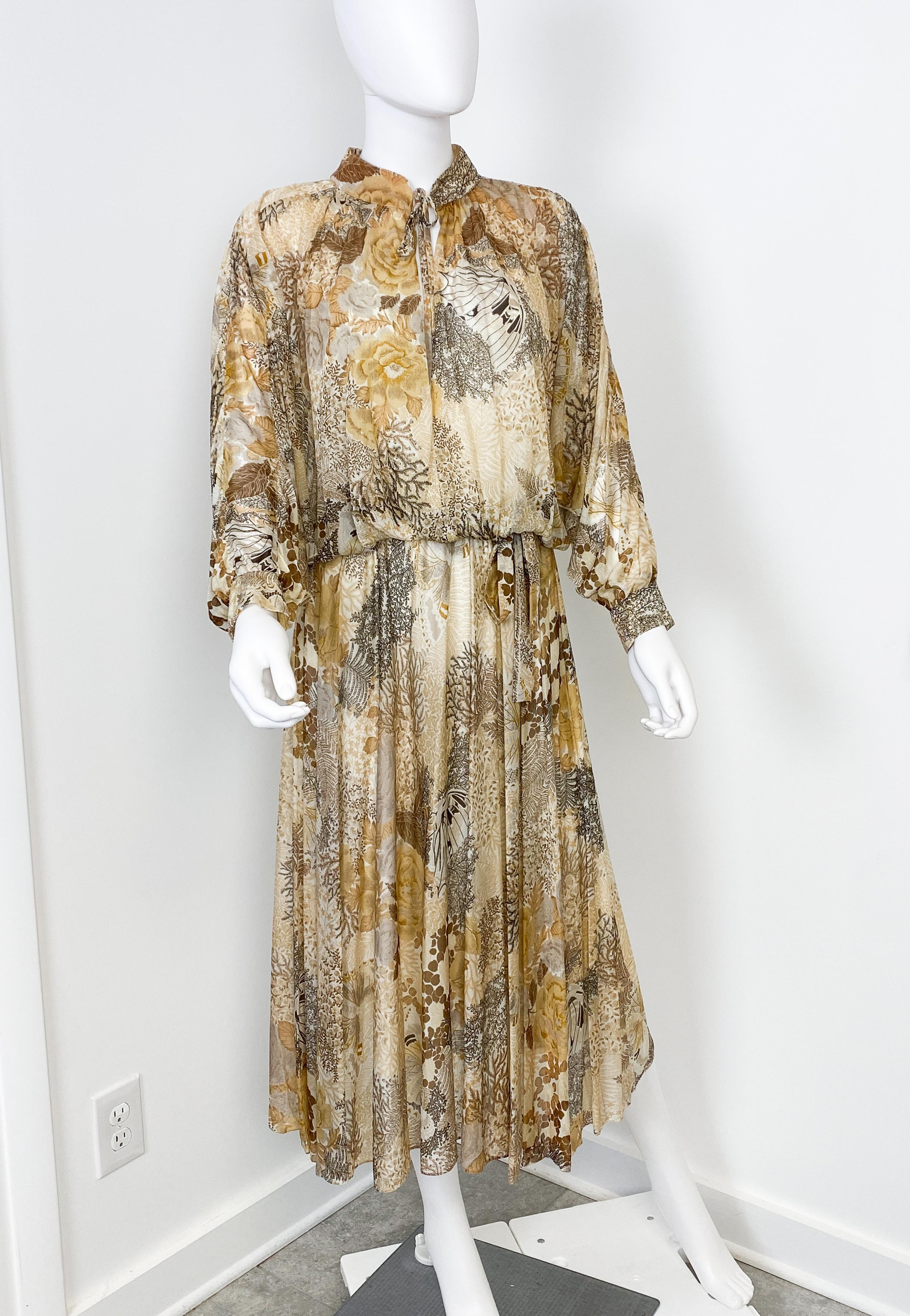 Voici une superbe robe de cocktail vintage en mousseline de jersey datant des années 1970. Il présente une silhouette fluide typique de l'époque, avec de longues manches chauve-souris ouvertes et une jupe ample et tourbillonnante. Le col mandarin