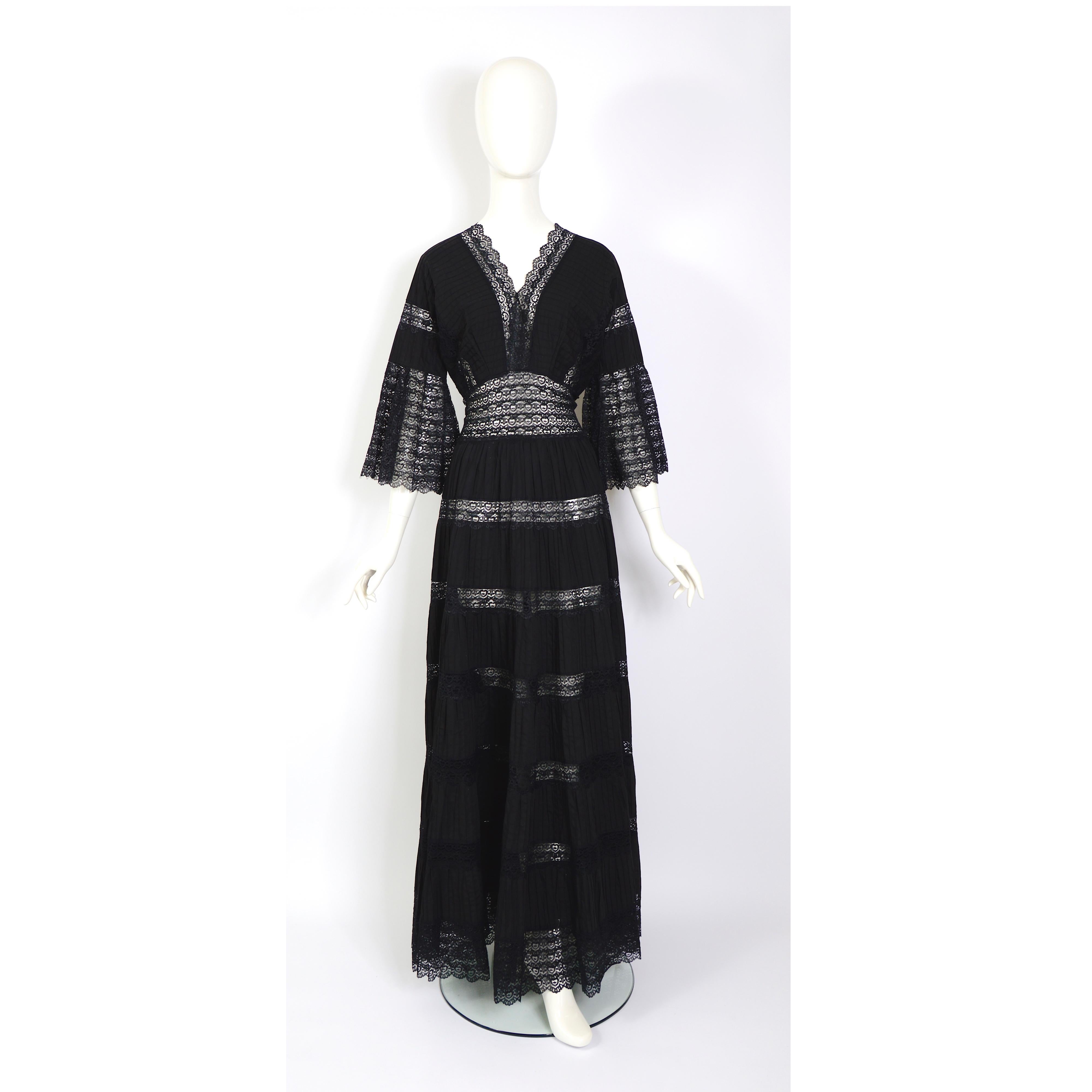 A great Mexican vintage 1970s evening gown in cotton and lace, this jet black gown is a real head-turner. The dress has a v neckline at the front and back, with pintuck cotton and lace panels. There is central back zip, and fluted sleeves trimmed