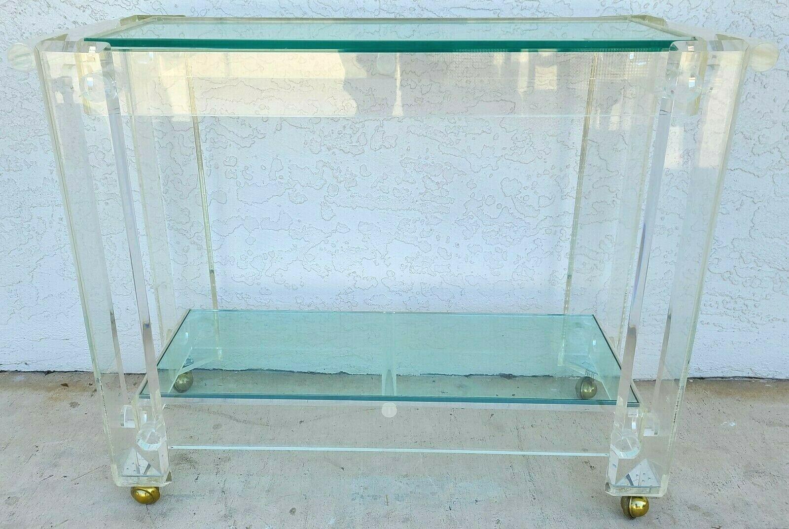 For FULL item description click on CONTINUE READING at the bottom of this page.

Offering one of our recent Palm Beach Estate fine furniture acquisitions of a
Vintage 1970s Thick Lucite & glass rolling bar serving cart with vintage shepard