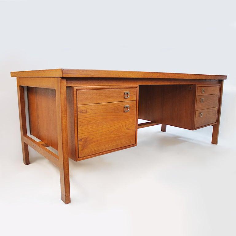 This is a wonderful executive desk designed by Arne Vodder for Danish furniture manufacturer H.P. Hansen. 

Desk Features:

- Book-matched teak veneer
- Solid teak frame
- Brushed aluminum hardware
- Five drawers

Dimensions: 69