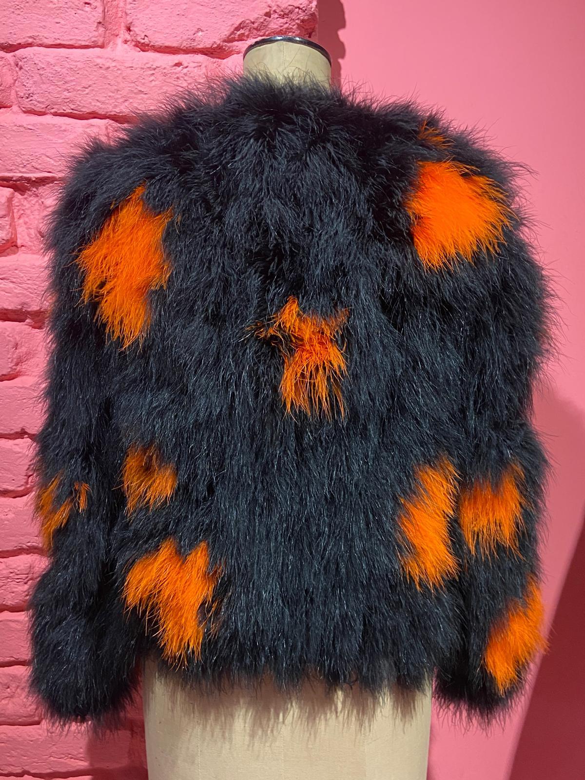 We are excited to present this 1970's Miss Dior by Christian Dior Black/Orange Maribou Feather Jacket .The piece features a blend of black and orange maribou feathers and cuts off just above the hips. The jacket is lined with a silky black fabric