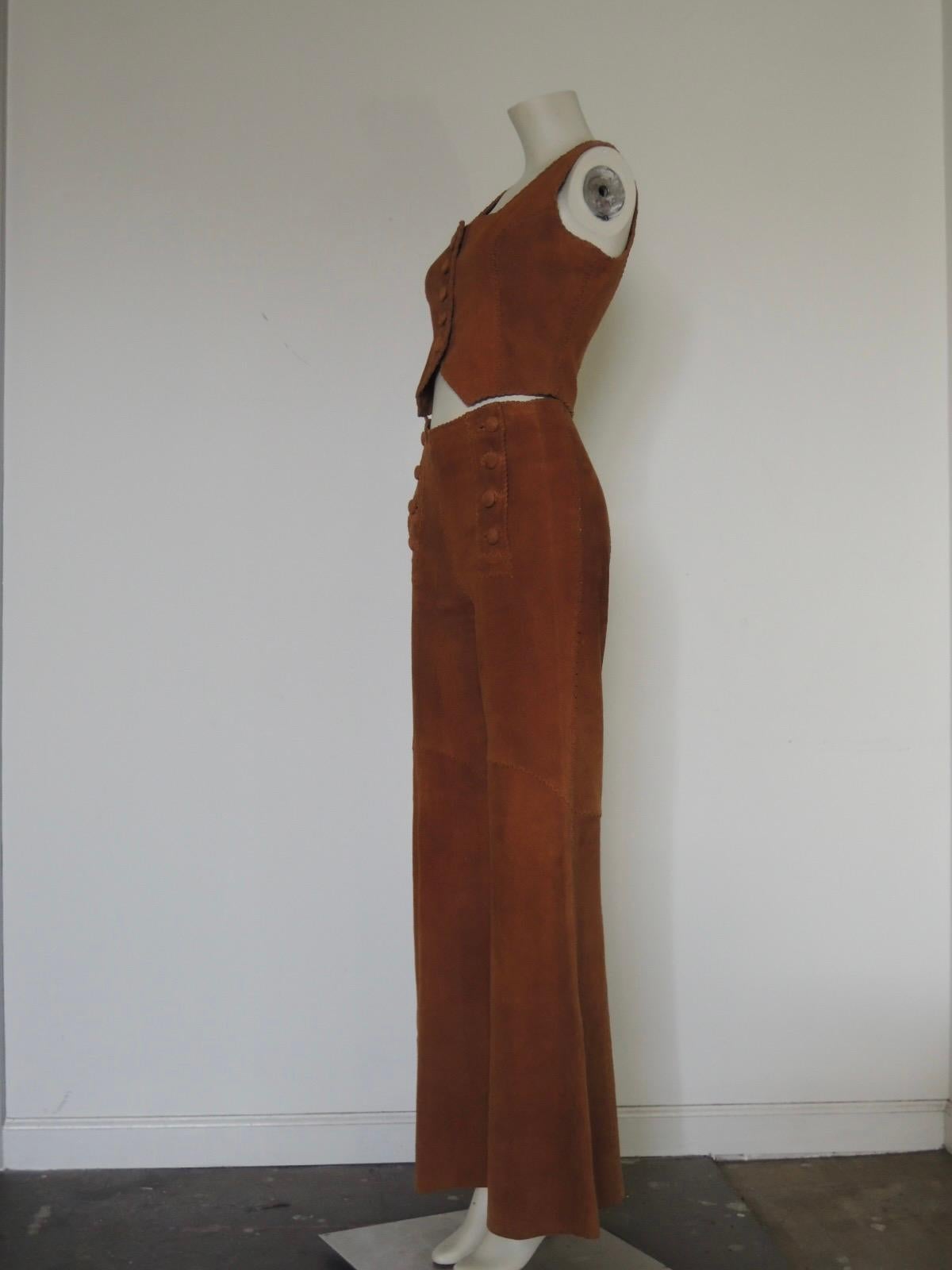 This is a vintage North Beach Leather suede set of pants and vest. Vintage 1970s handmade North Beach Leather suede leather pants in a sailor-pant style. Whipstitch construction, 8-button front  A hippie crop vest completes the set.

These are in