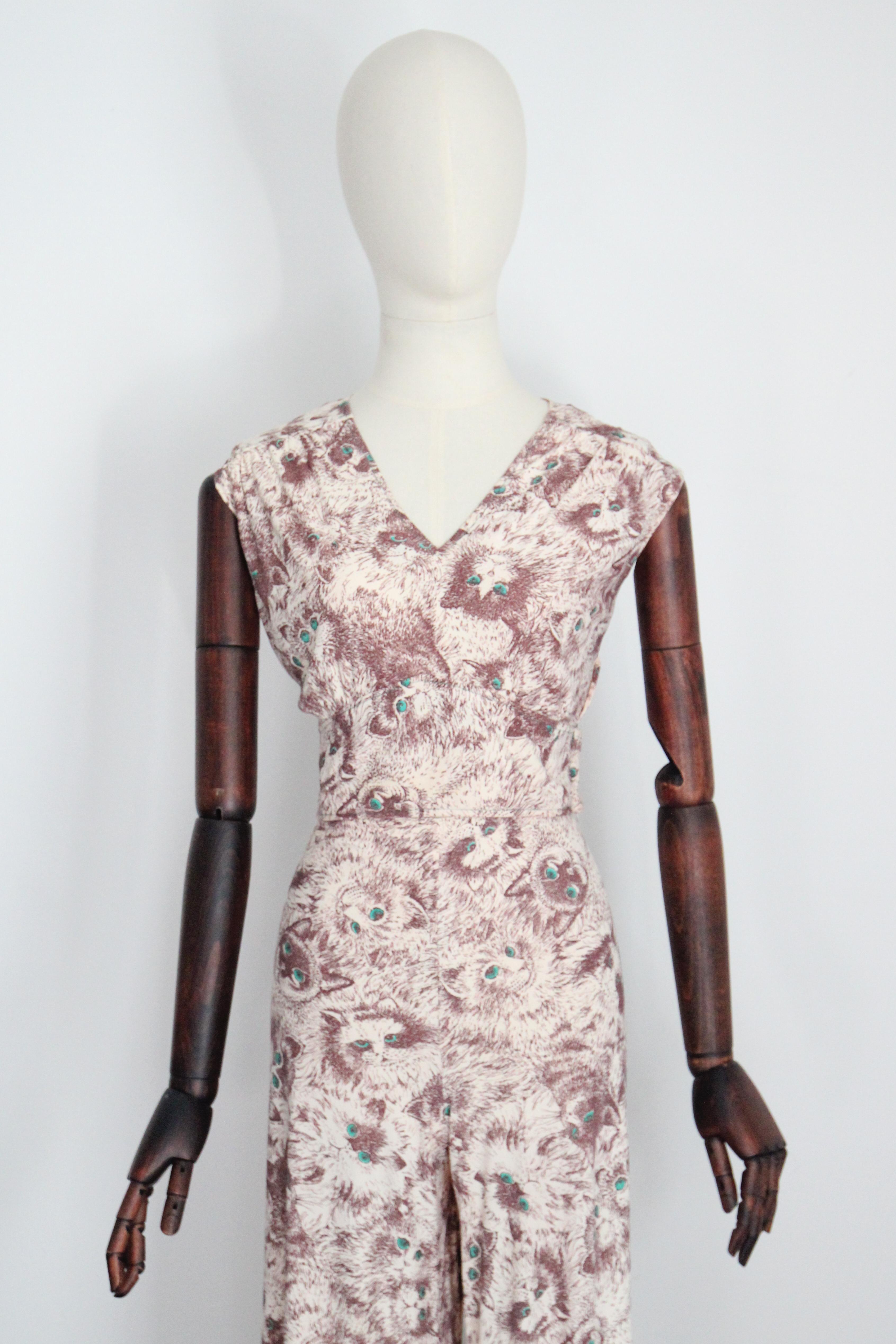 Questo fantastico abito a tre pezzi degli anni '70, reso con un'accattivante stampa di gatti, in stile schizzato marrone, accentuata da occhi verdi su uno sfondo color crema, è l'insieme perfetto da aggiungere alla tua collezione vintage. 

Il