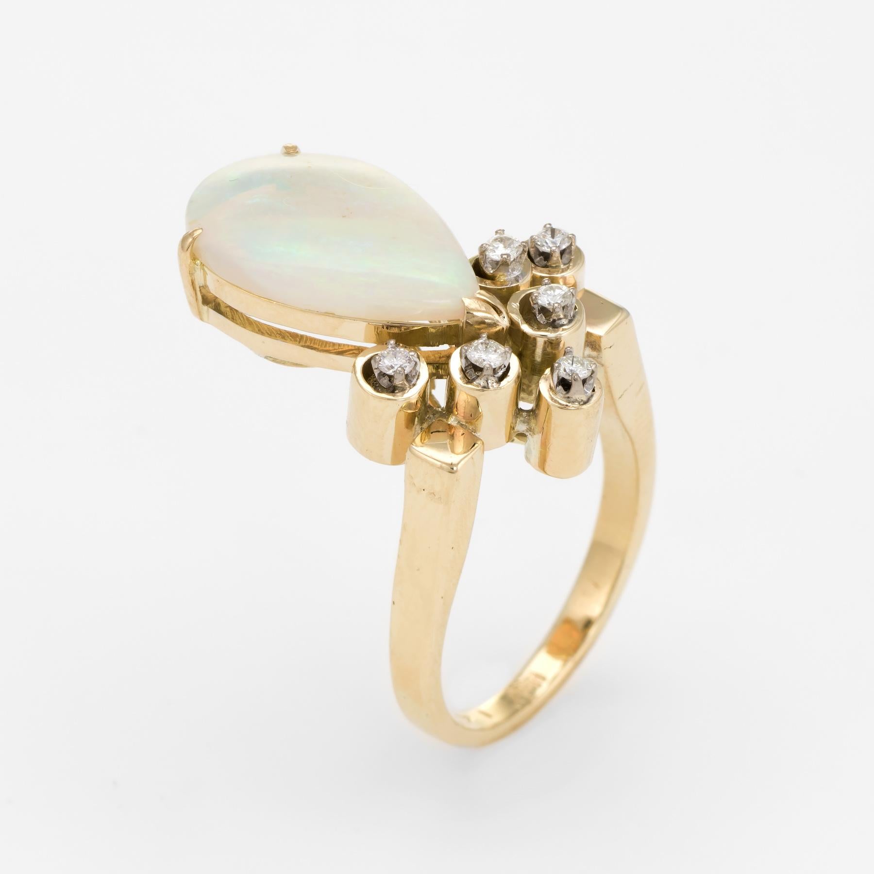 Distinct & stylish opal & diamond cocktail ring (circa 1970s), crafted in 14 karat yellow gold. 

Centrally mounted natural opal is pear cut, measuring 17mm x 11mm (estimated at 8 carats), accented with six estimated 0.03 carat round brilliant cut