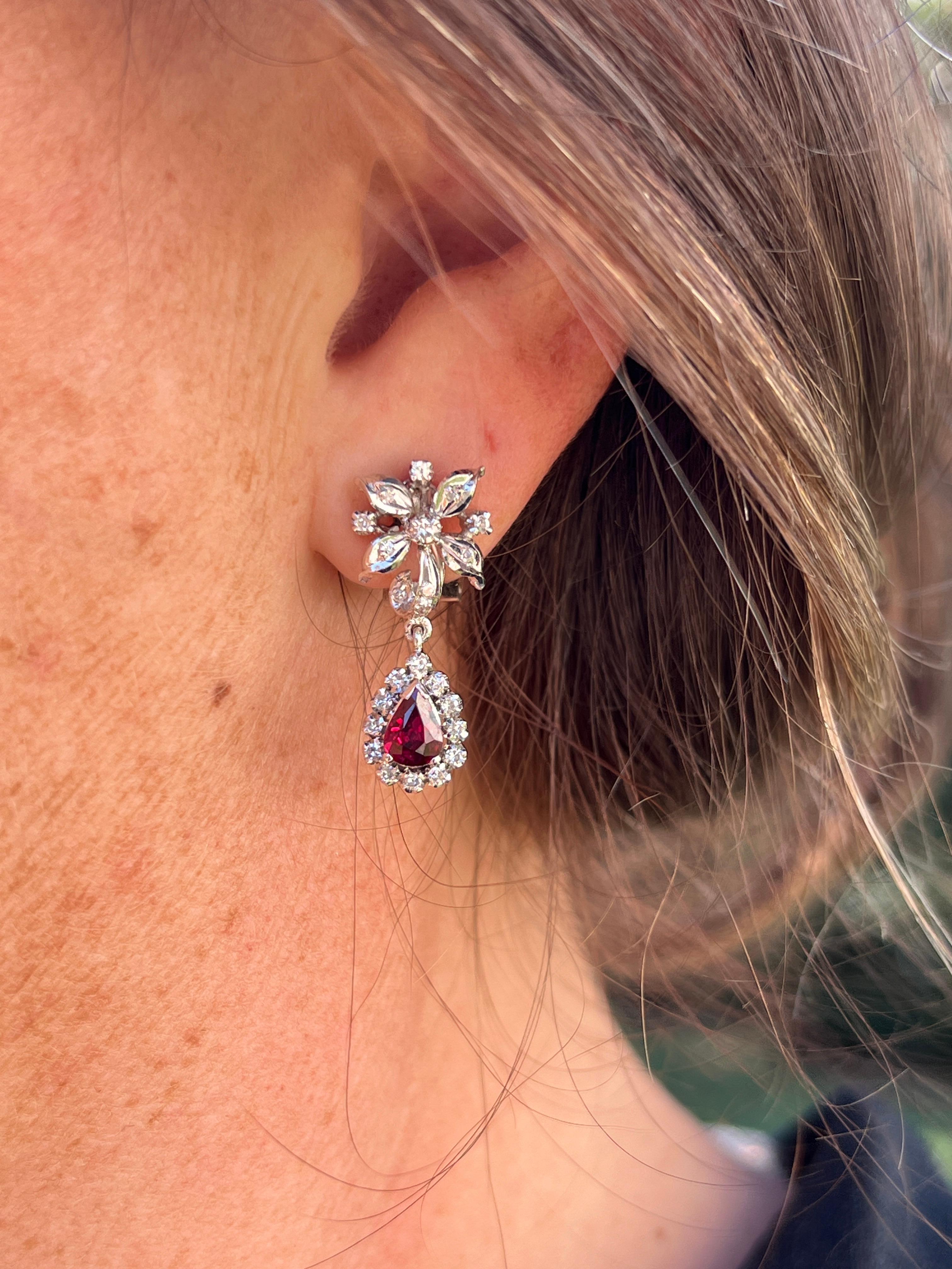These vintage 1970s 14K white gold earrings feature a floral motif with a  sophisticated pendant cluster design, set with two vibrant 6x4mm pear-shaped natural fine red rubies. Accented by forty-eight single-cut diamonds, approximately 0.50 total