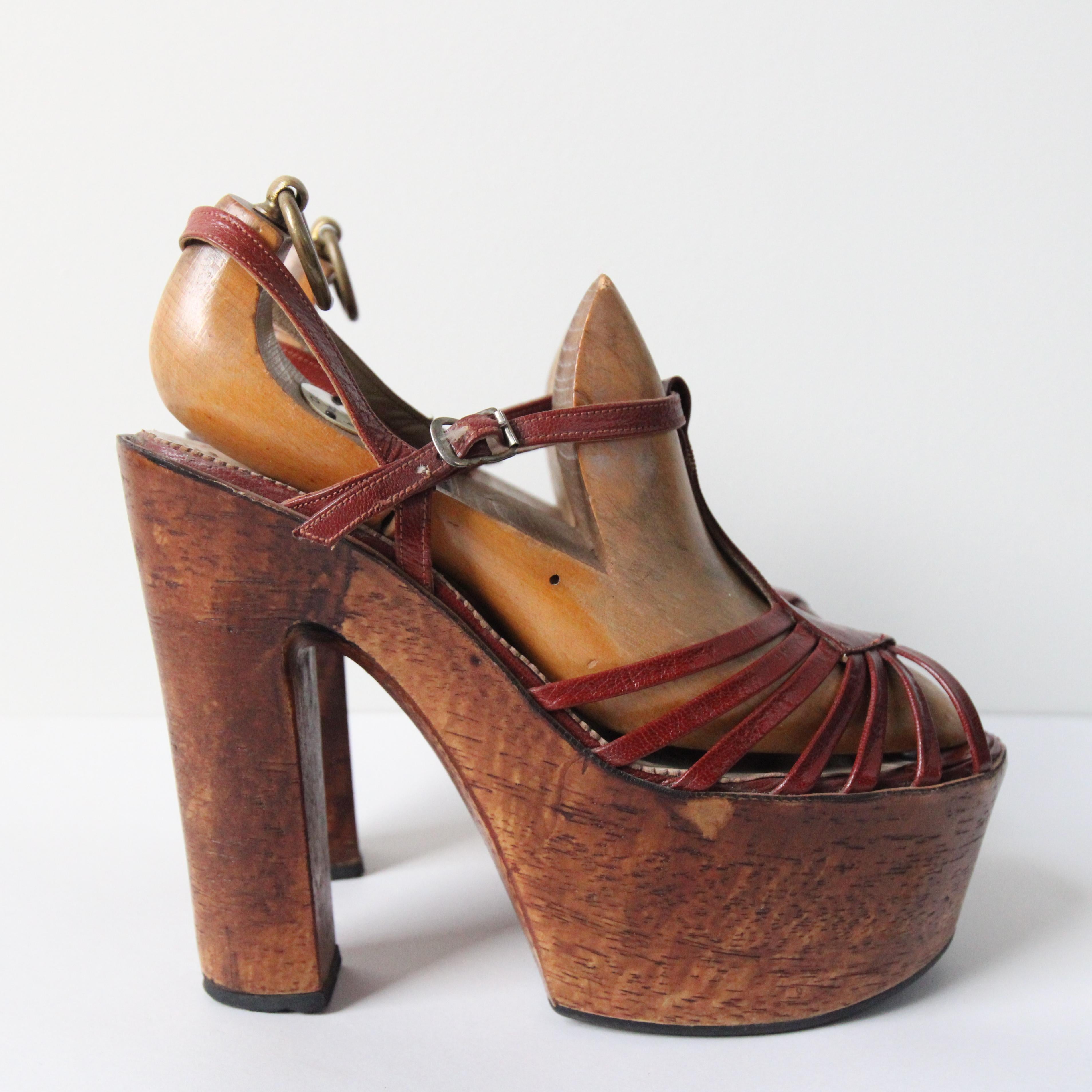 The most iconic pair of 1970's French platforms you could ever hope to set eyes upon.

The elegant wooden platform, showcases a rounded open toe cut. The sandal design of the shoe, boasts a T bar design, which features a diamond shape along the