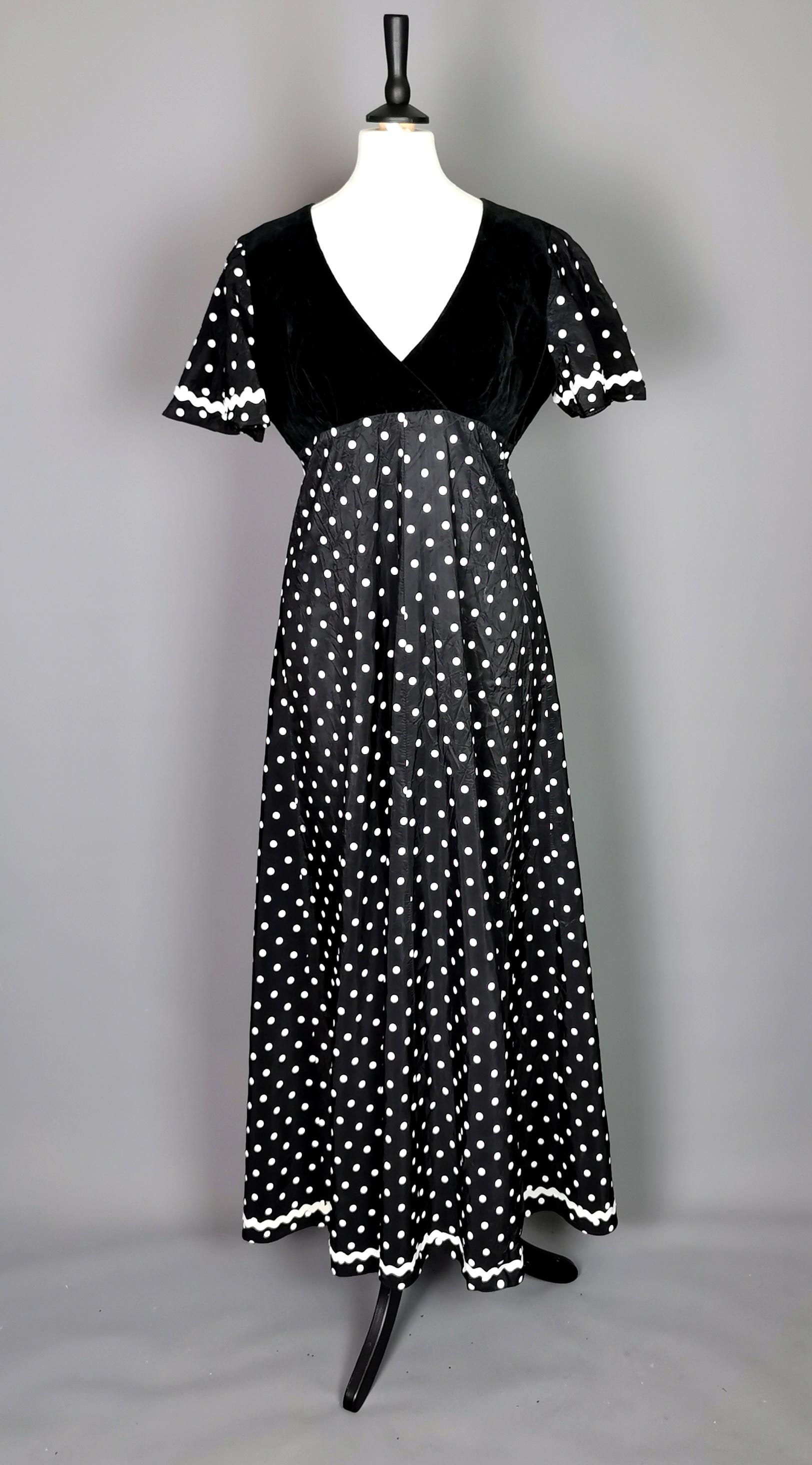 A fab vintage 1970s maxi dress by Dolly Rockers.

Made in England from a rayon / nylon synthetic blend fabric with a slightly shiny finish, it has an all over white polka dot design with a black velvet bodice and short sleeves.

An unusual Dolly