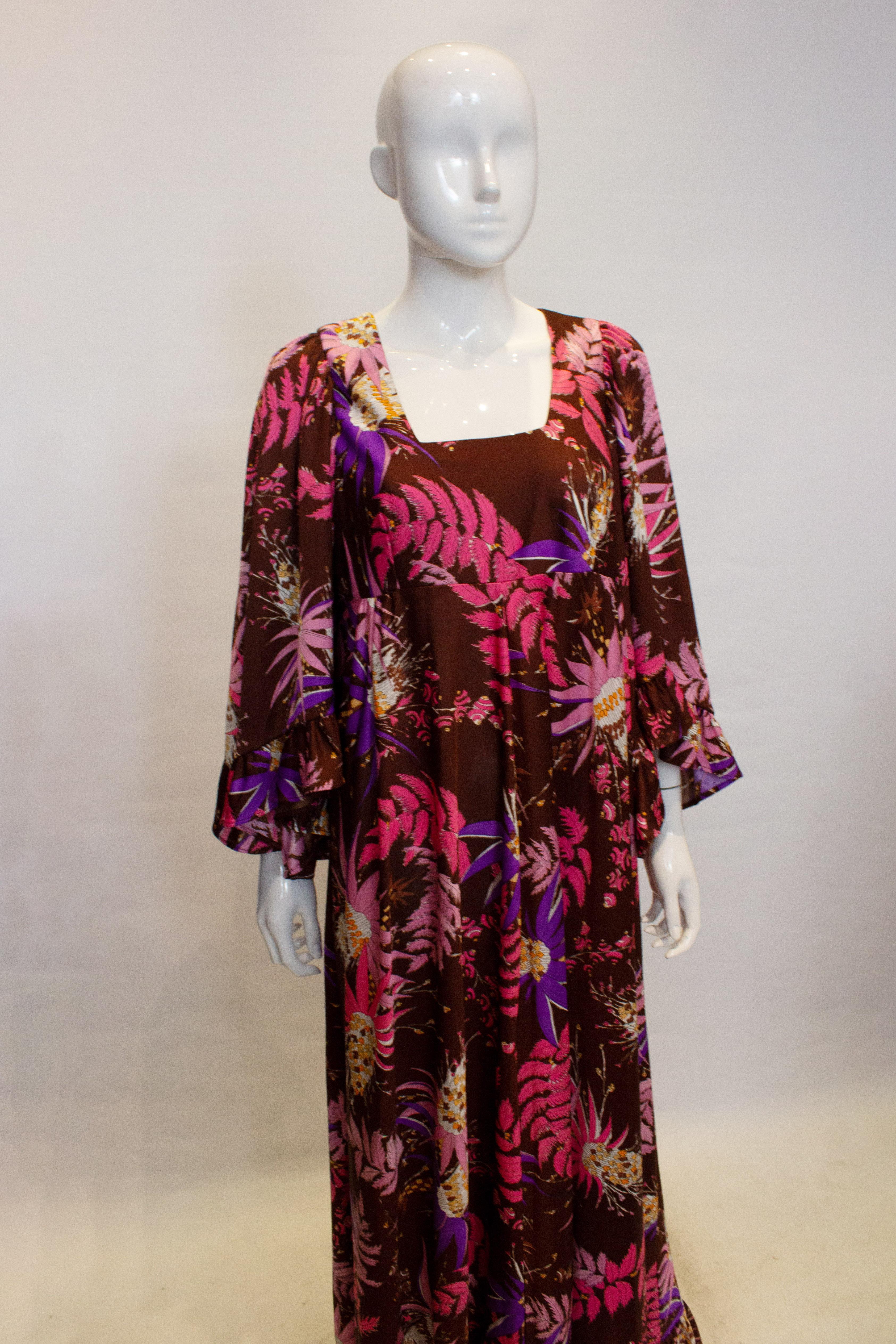 A great vintage party dress from the 1970s. The dress  has a brown background with an attractive print in pink, white and brown. it has  low square neckline with elbow length sleaves and a back central zip. Measurements Bust 39'',lenght 61''