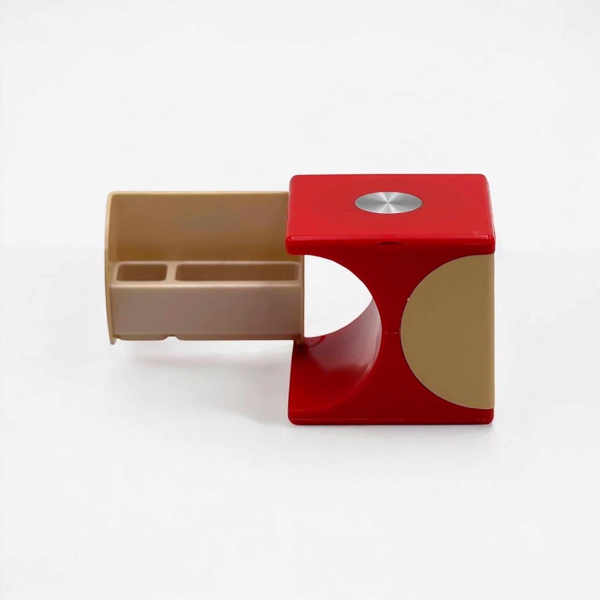Ce vanity box vintage des années 1970 est un exemple frappant du design fonctionnel de l'âge de l'espace. Fabriqué en plastique rouge brillant, il se présente comme un cube minimal lorsqu'il est fermé, puis s'ouvre pour révéler un miroir de taille