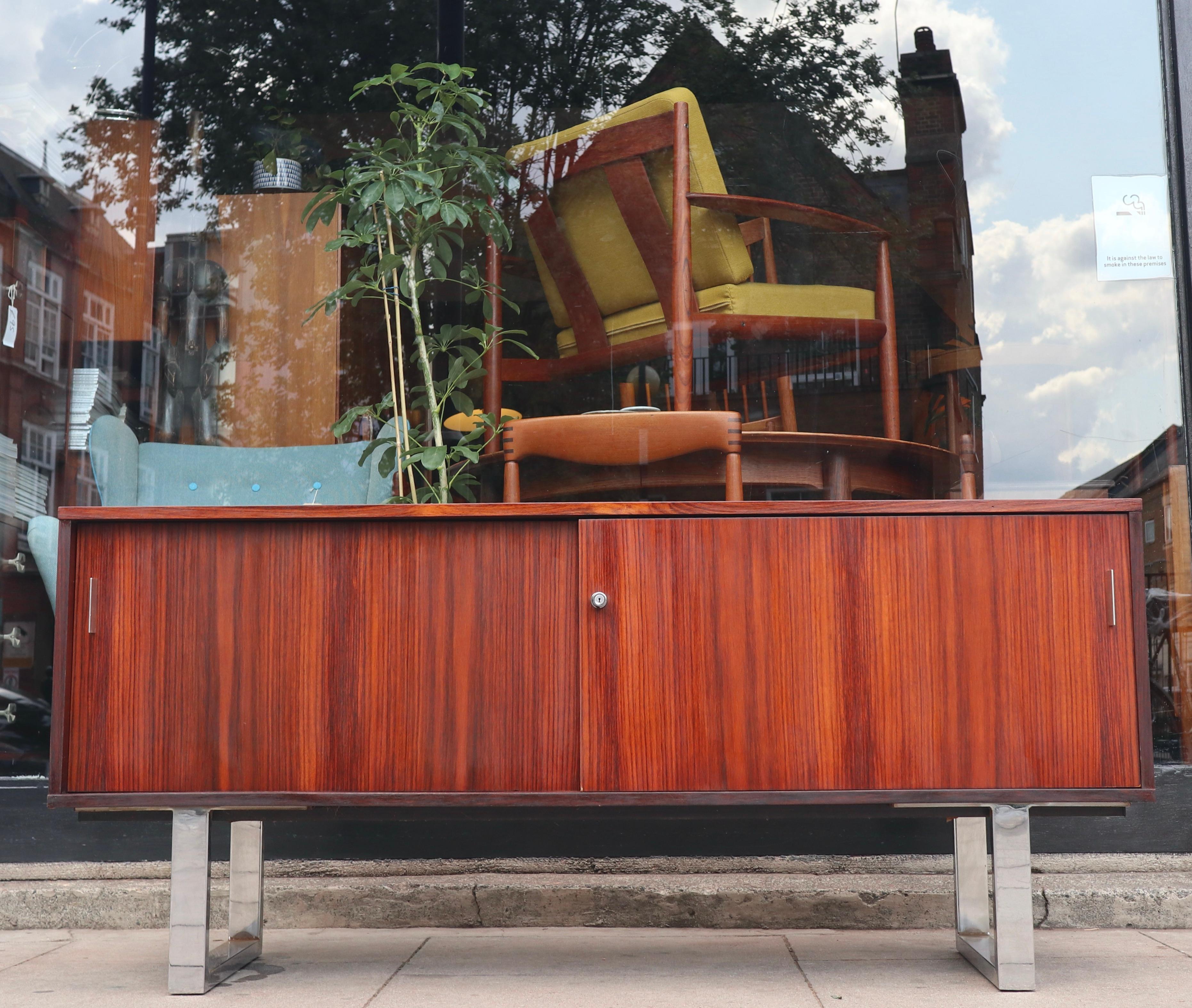  1970s Mid-century rosewood veneer credenza sideboard by Trevor Chinn for Gordon Russell circa 1970, constructed from rosewood and raised on chrome sleigh legs, the rectangular top over two sliding cupboard doors with one central lock.

