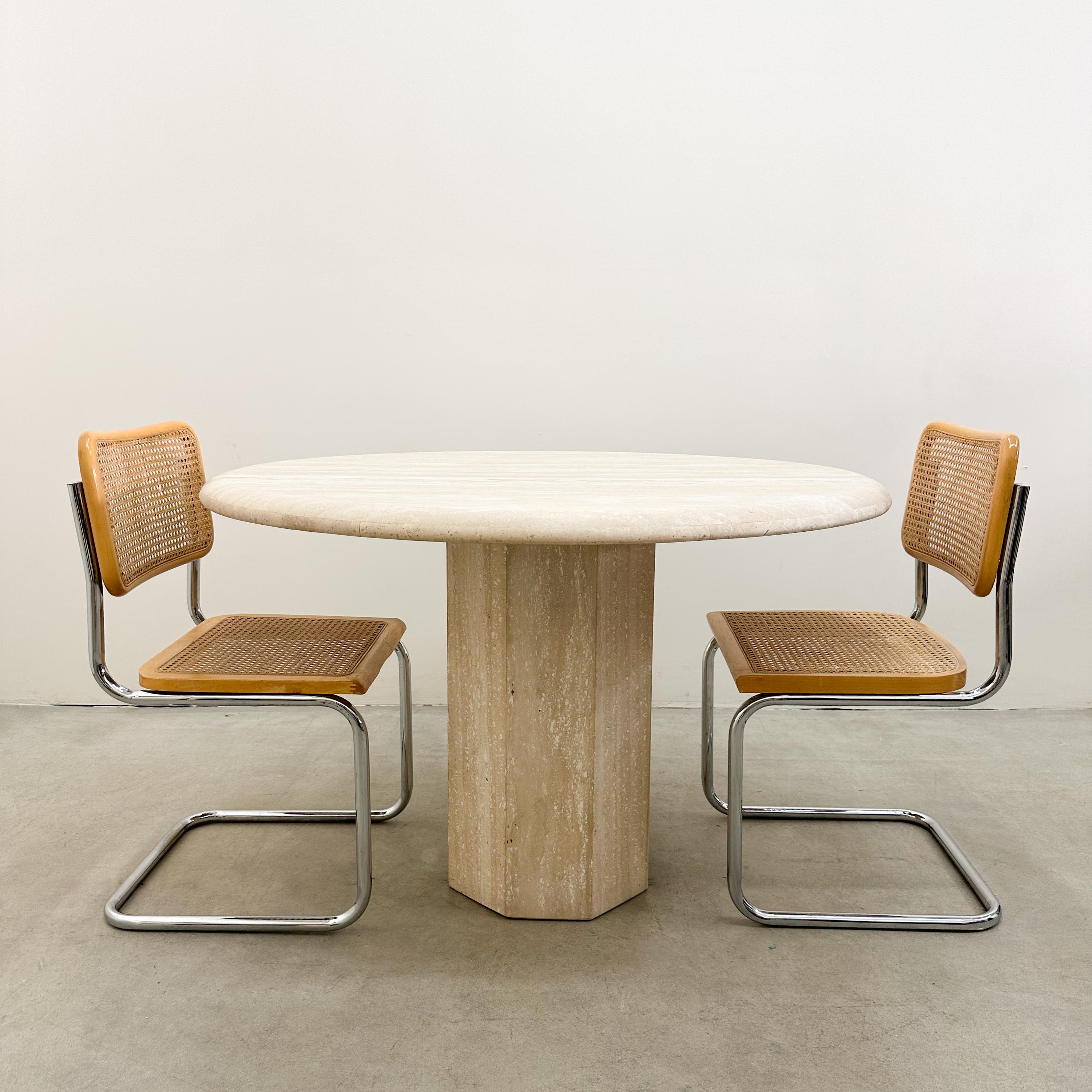 This vintage round travertine dining table from the late 1970s embodies timeless elegance and Mid-Century Modern design. The solid travertine top rests on a sturdy pedestal base, creating a sculptural yet functional piece that blends seamlessly into