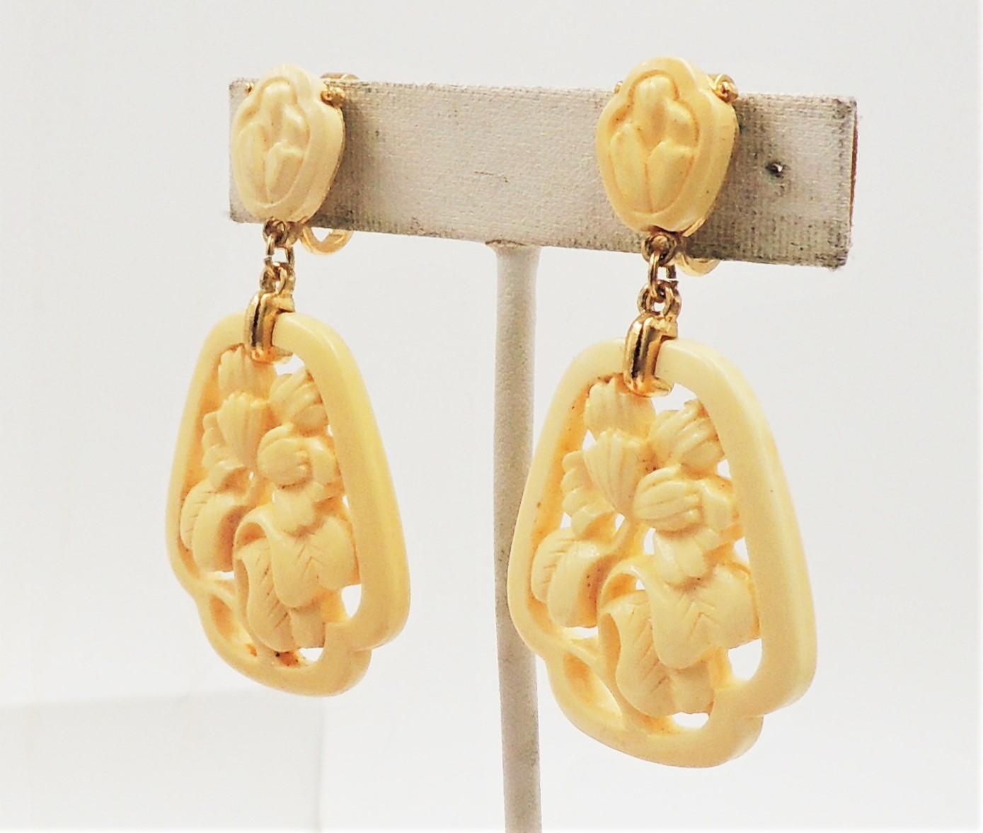 Early 1970s goldtone and ivory colored Lucite flower drop clip back earrings. Marked crown 