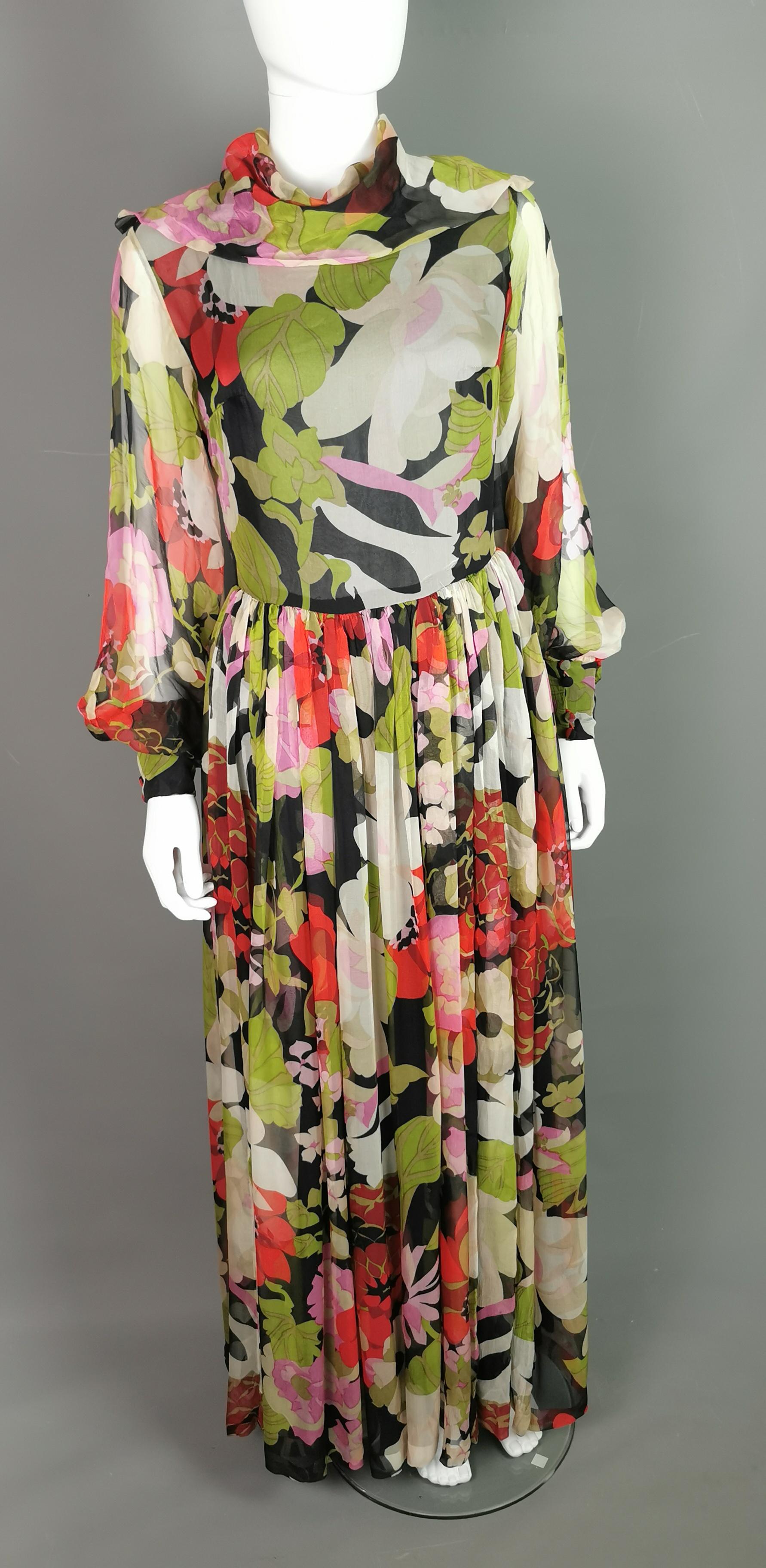 Das schönste geblümte Maxikleid aus den 1970er Jahren.

Das Kleid ist aus herrlich weichem, durchscheinendem Seidengeorgette gefertigt, das mit einem Blumenmuster auf dunklem Grund bedruckt ist. Es hat einen ungewöhnlichen Kuttenausschnitt und