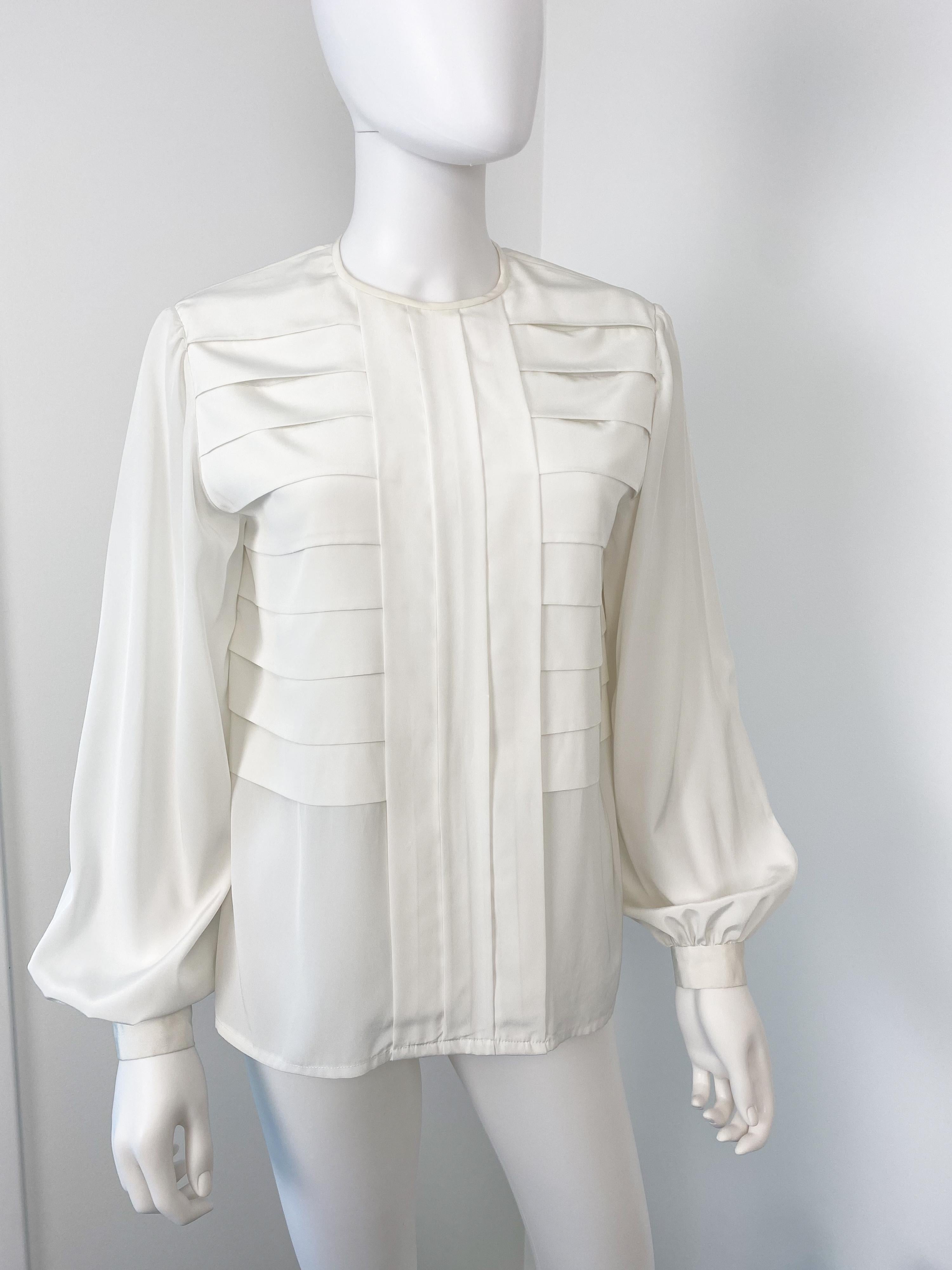 Wonderful vintage 1970s silky polyester blouse. White color fabric with geometric origami pleats. Buttons closing at the back and crewneck shape. There is gentle pleating at button cuffs to provide volume.

Brand: Unknown
Model: Polyester
