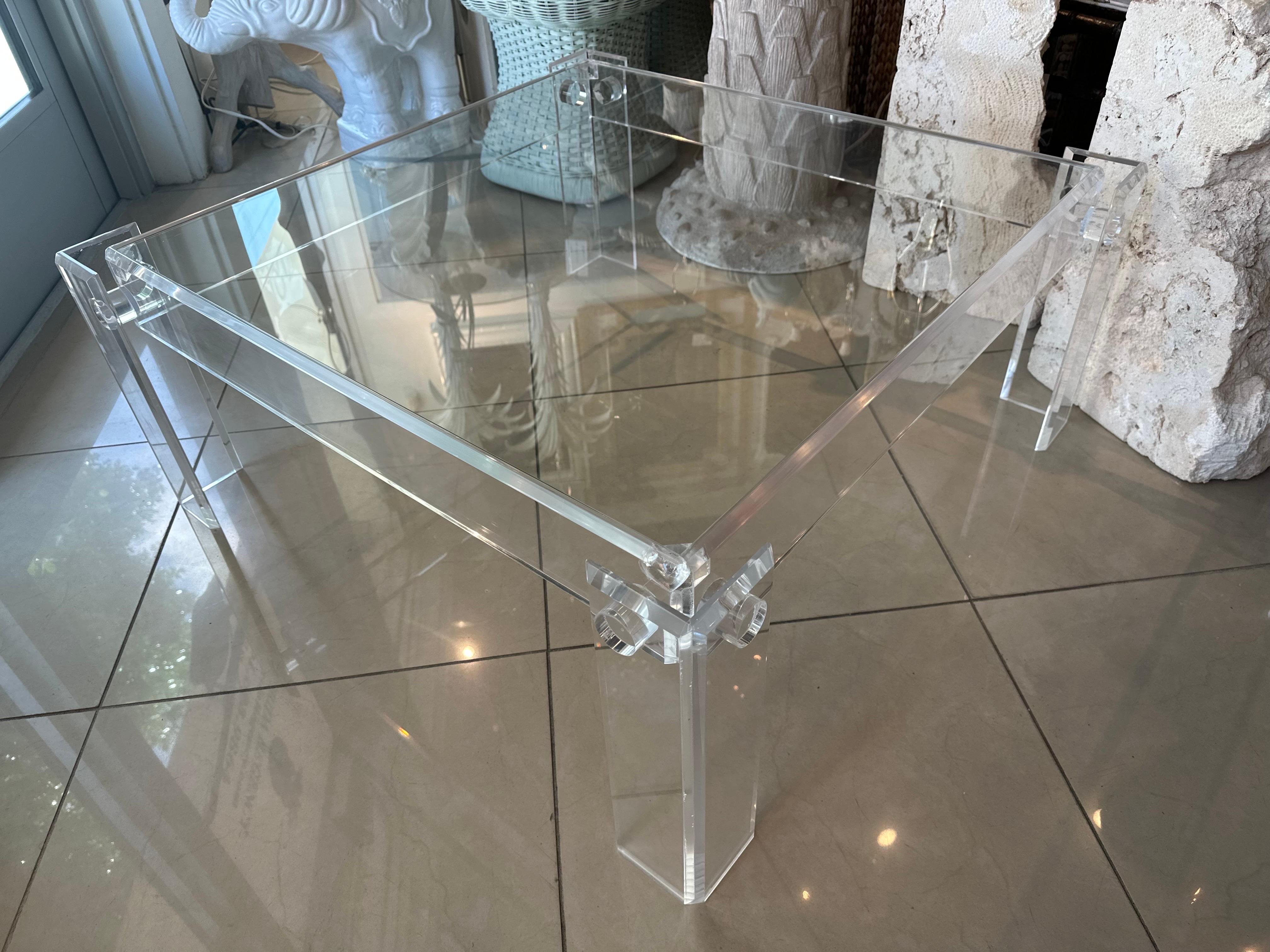 Table à cocktail vintage carrée en lucite avec plateau en verre. Le plateau en verre est neuf. La lucite a été polie. Petites rayures et imperfections sur la lucite. Dimensions : 15 H x 36 D x 36 W. Le plateau est de 33 x 33. 