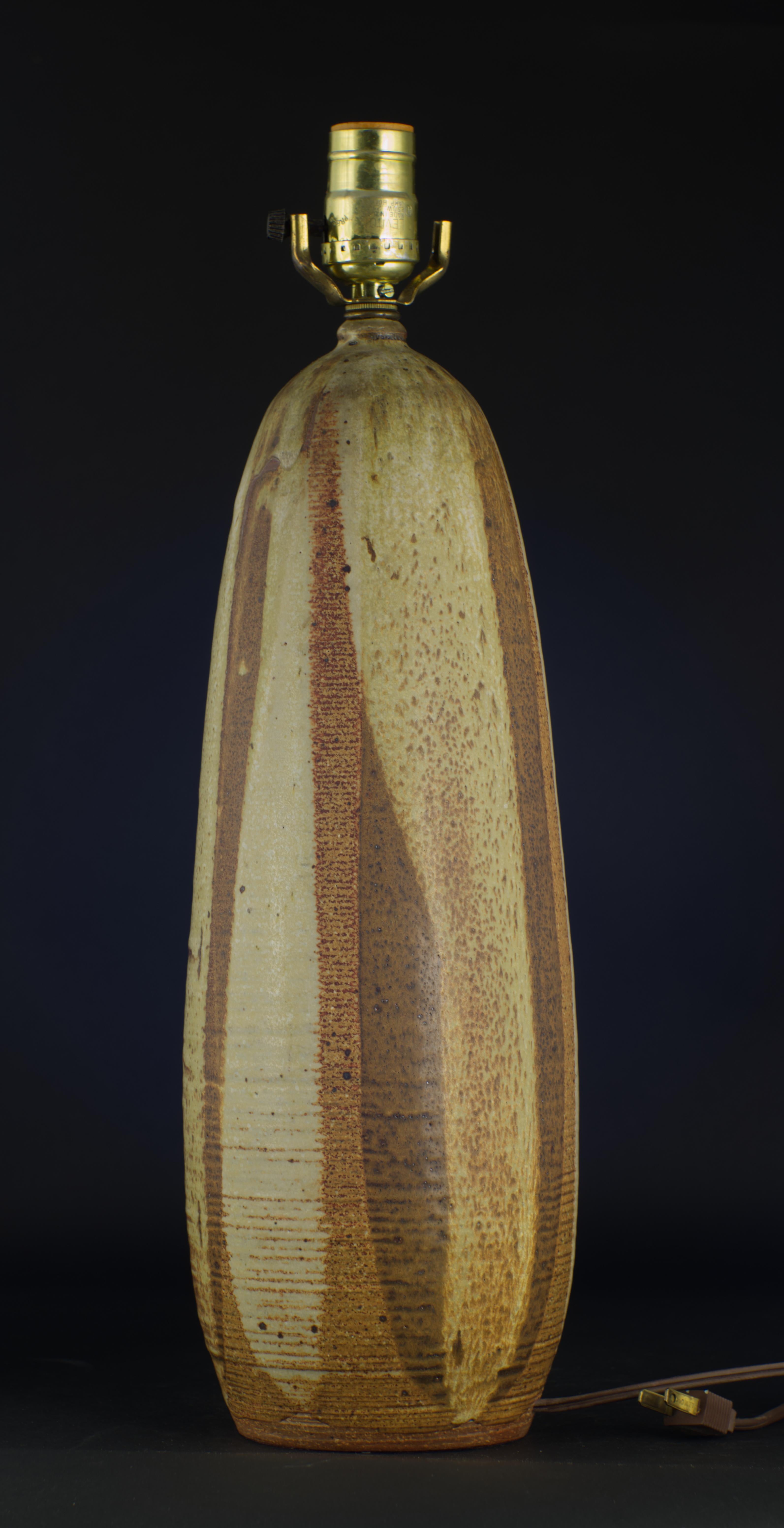  Lampe de table en céramique vintage des années 1970 décorée de stries verticales de glaçure semi-mate dans les tons bruns et gris sur un corps ovoïde allongé jeté à la main dans de l'argile rouge. La forme organique et les tons terreux de la