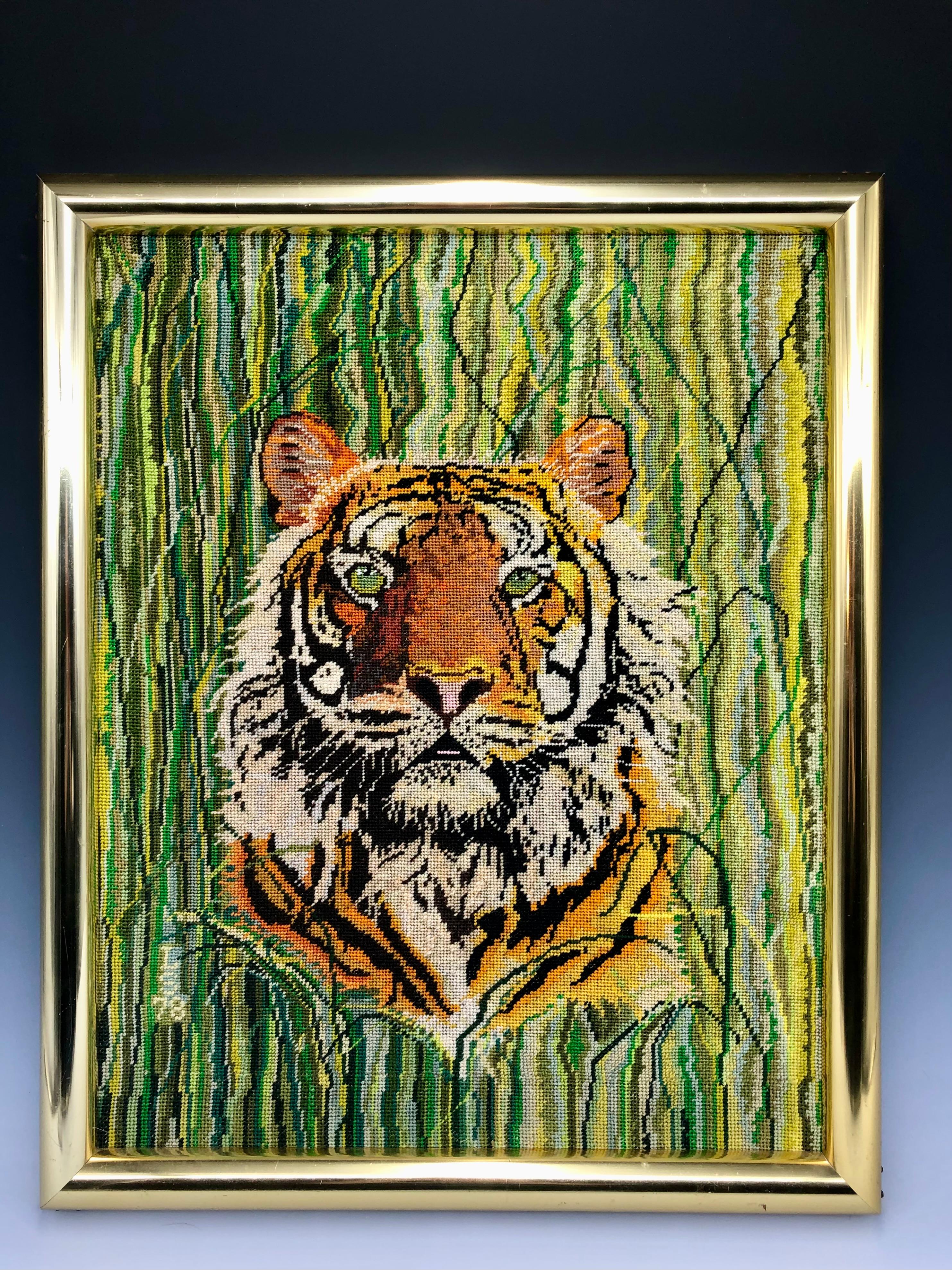 This striking 1970s embroidered tiger portrait has a striped green-toned grassy abstract background. 

The item comes framed in a thick brass frame. It is signed 