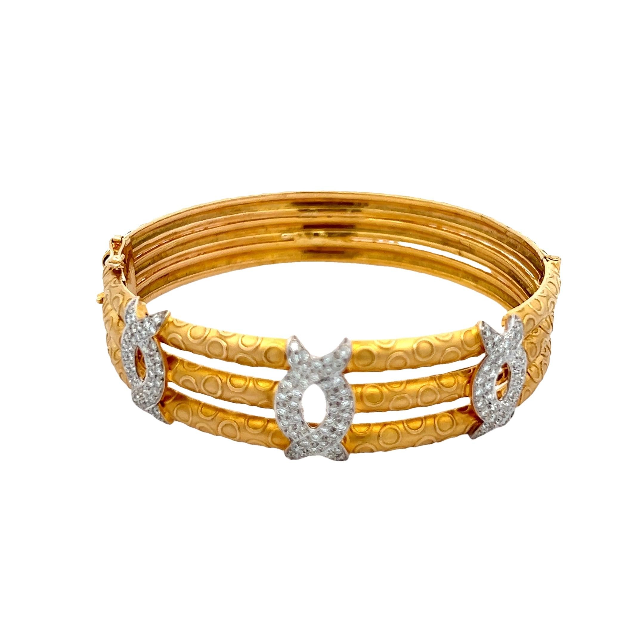 Elegant et distinctif, ce bracelet bangle vintage des années 1970 capture l'esthétique audacieuse mais raffinée de l'époque. Réalisée à la main en or jaune 18 carats, cette pièce présente une structure à trois rangs avec un motif circulaire unique