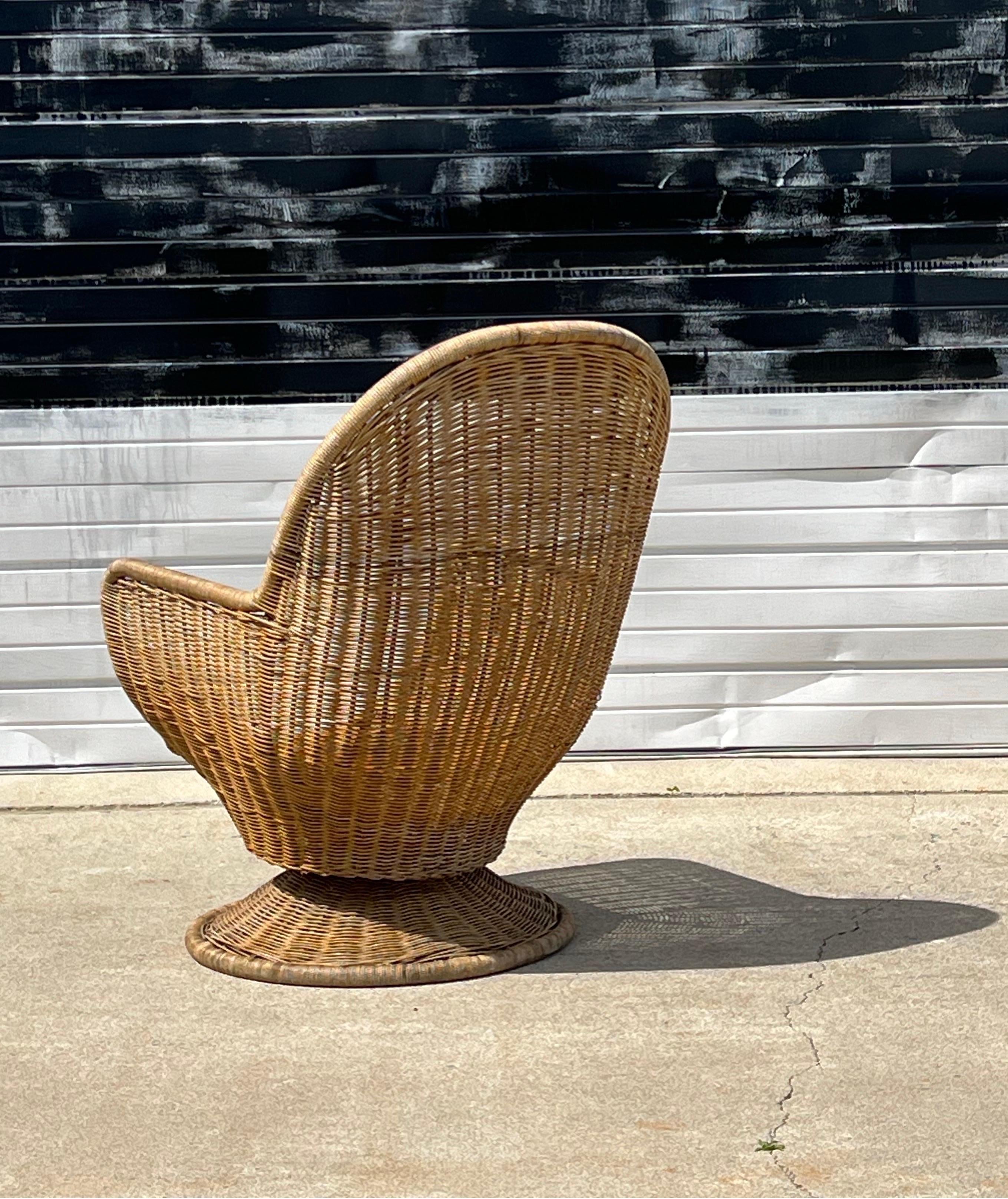 Sedia girevole di metà secolo in vimini e rattan. Realizzato negli anni '70 circa, negli Stati Uniti. Poltrona a forma di uovo con molte curve e bordi arrotondati. Questo pezzo poggia su una base circolare in rattan. Puoi usarlo così com'è o