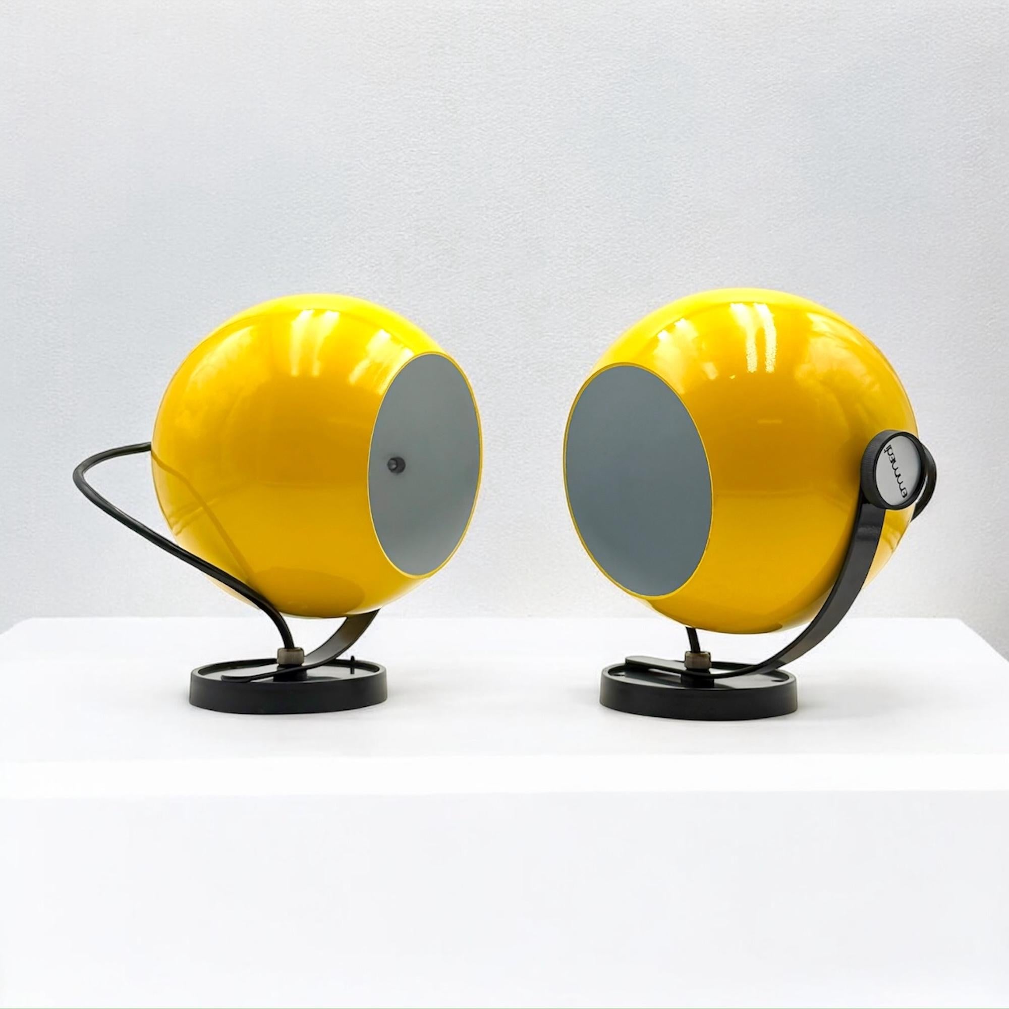 Llamativo par de apliques de los años 70 fabricados en Italia por Emmedi. Estas icónicas piezas presentan una brillante pantalla de metal esmaltado en amarillo con elegantes detalles en negro, que encarnan el espíritu juguetón pero sofisticado de la