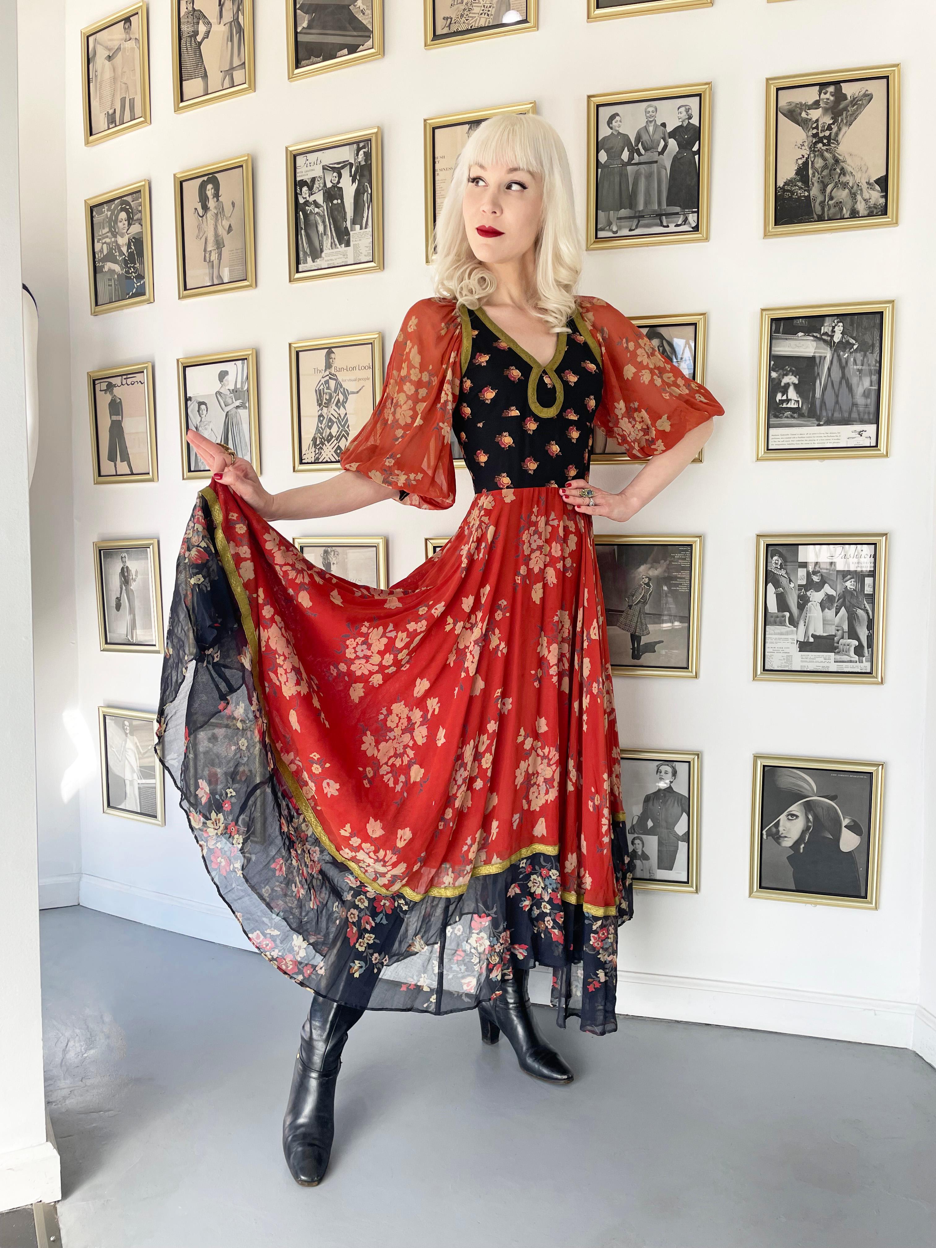 Gorgeous 1971 Thea Porter documented designer dress fashioned in a magical semi-sheer floral print black and red voile cotton. The stunning fabric is trimmed in metallic gold that has a touch of shimmer which I adore. The bodice has a closed