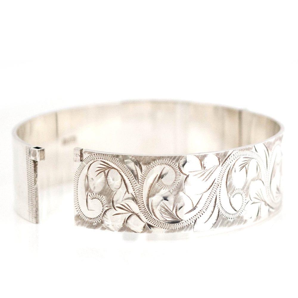 Embrace the bold style of the 1970s with this wide silver bangle, a standout piece hallmarked in the renowned Birmingham Assay Office in 1976. The bangle presents a classic yet striking design, featuring a distinctive engraving on one side that adds