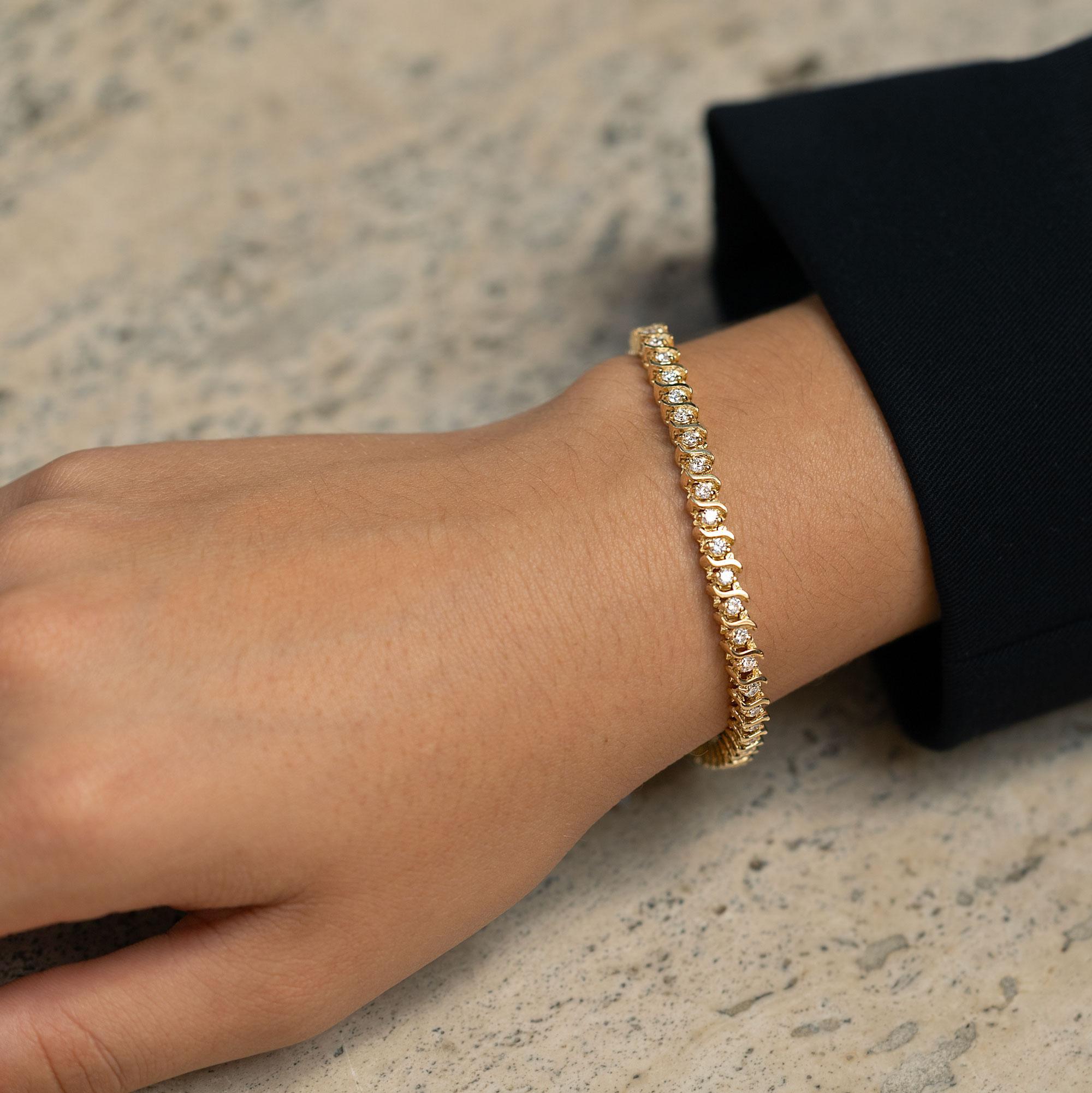 A vintage classic with a twist, this 1980s S link diamond tennis bracelet is the perfect choice for a fashionable yet affordable gift. A total of 1 and a half carats of sparkling round diamonds embrace this 14k yellow gold jewel. The well matched