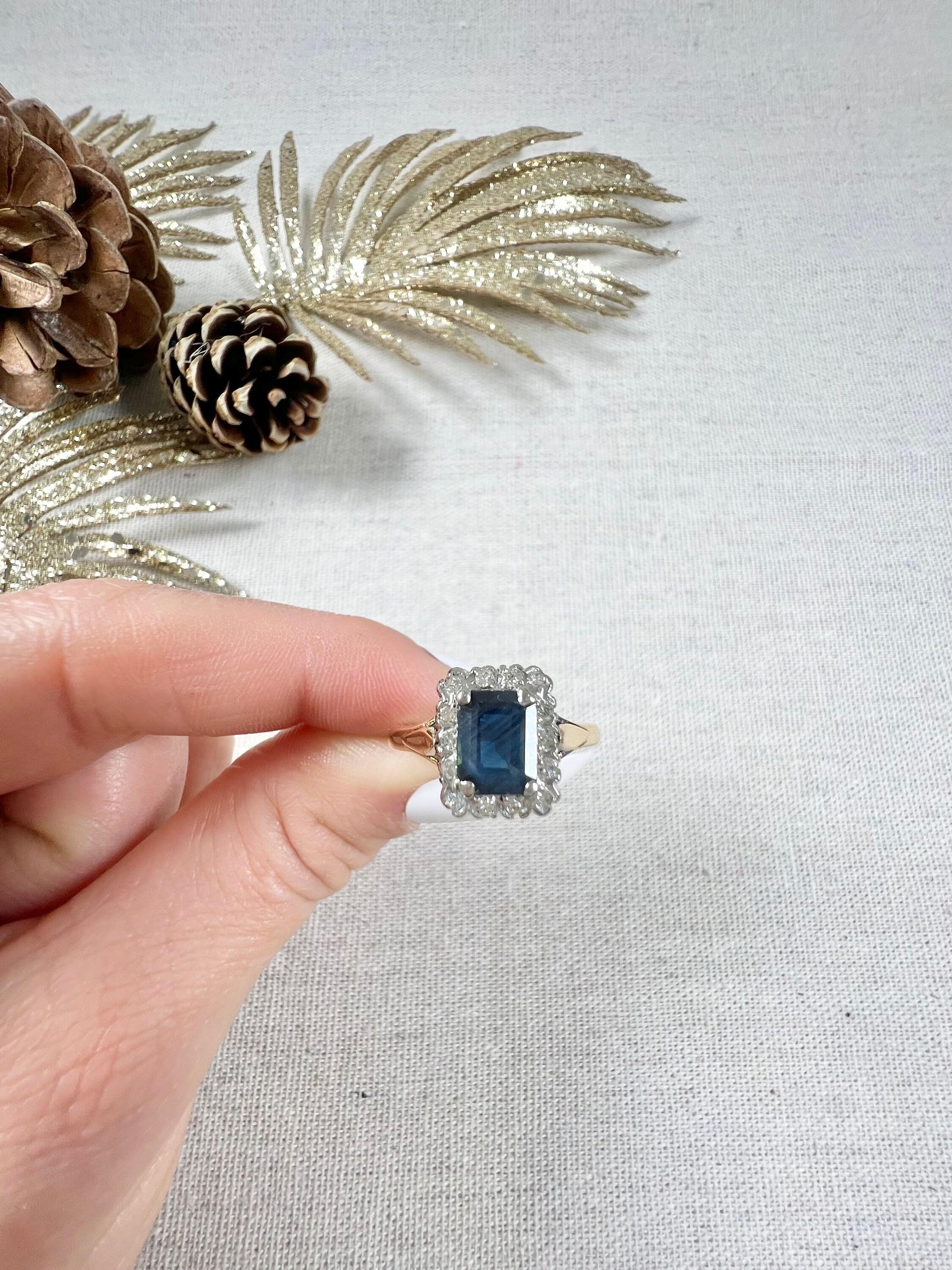 Vintage Sapphire & Diamond Ring 

18ct Gold Stamped 

Circa 1980s

This stunning vintage ring is truly a one-of-a-kind piece. Crafted from both yellow and white 18ct gold, this cluster ring features a beautiful emerald-cut natural sapphire stone at