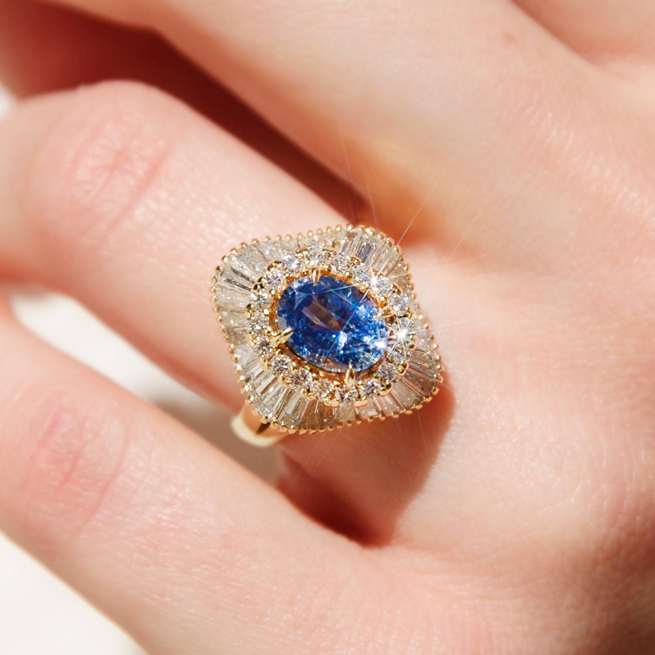 Expertly hand-crafted in 18 carat gold The Gianna Ring is glamour steeped in fortitude. Her bold sapphire, set in halos of undulating round brilliant and baguette diamonds, sparkles demands our reverence. Walk confidently through your world with
