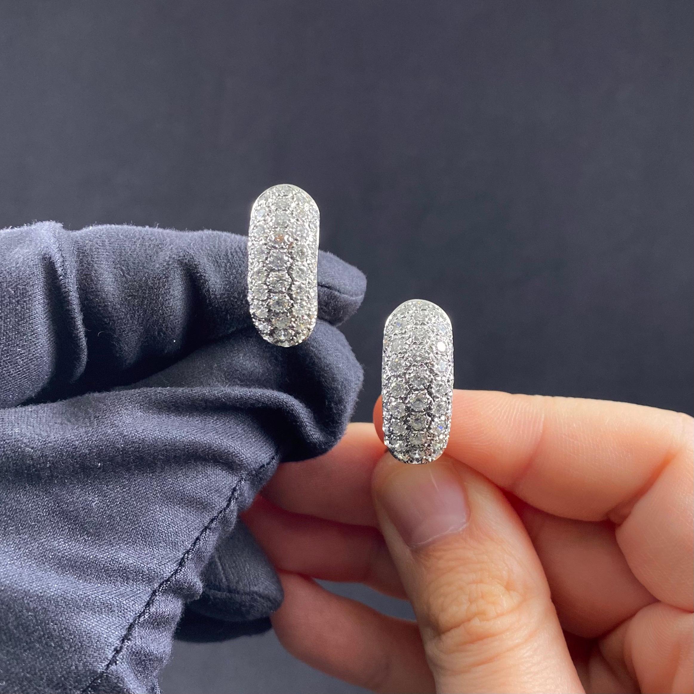 A pair of vintage pave-set diamond hoop earrings in 19.2kt white gold, Portugal, circa 1980s. Each earring of a dome design is seamlessly pave set throughout with 44 round brilliant-cut diamonds in open back settings, secured to reverse with a post