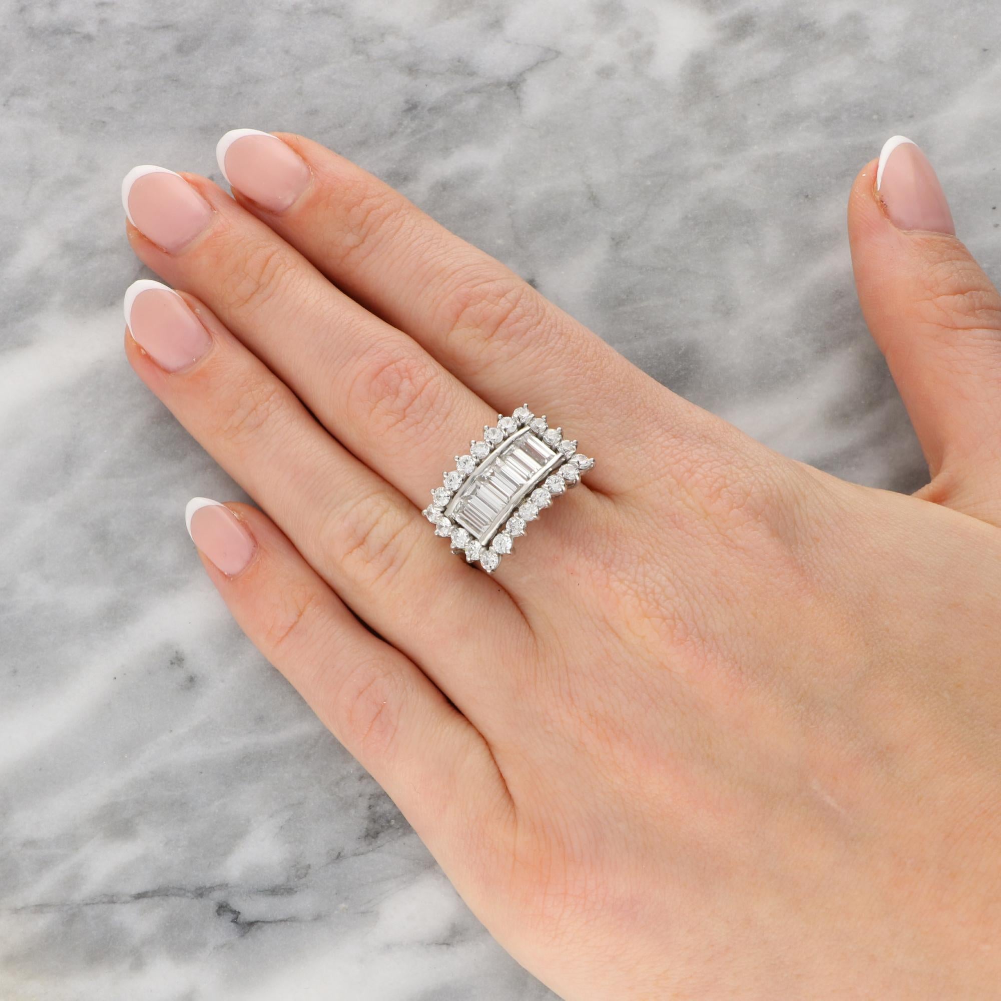 A stylish vintage 1980's baguette and round diamond statement ring set in 18k white gold.

The ring is centrally set with 5 graduating baguette cut diamonds which are securely bezel set. The baguettes are then surrounded by a cluster of 22 round