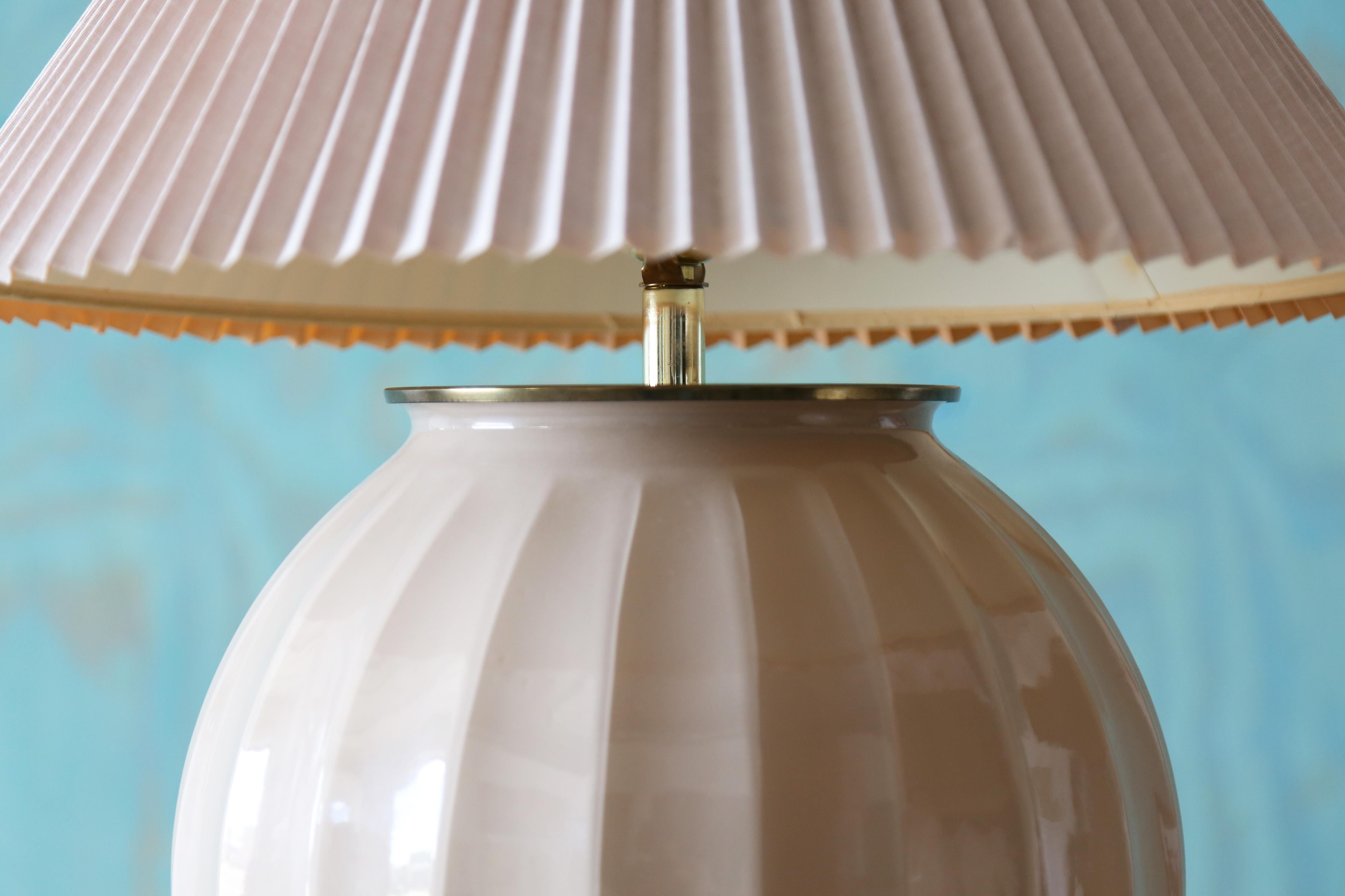 Ein Paar bauchige Designerlampen, bestehend aus einem rückseitig bemalten Glaskörper und plissierten Schirmen. Eine perfekte Mischung aus Creme und Blush, mit Messingbeschlägen. Diese Lampen haben es in sich und werden Ihre Einrichtung mit Stil