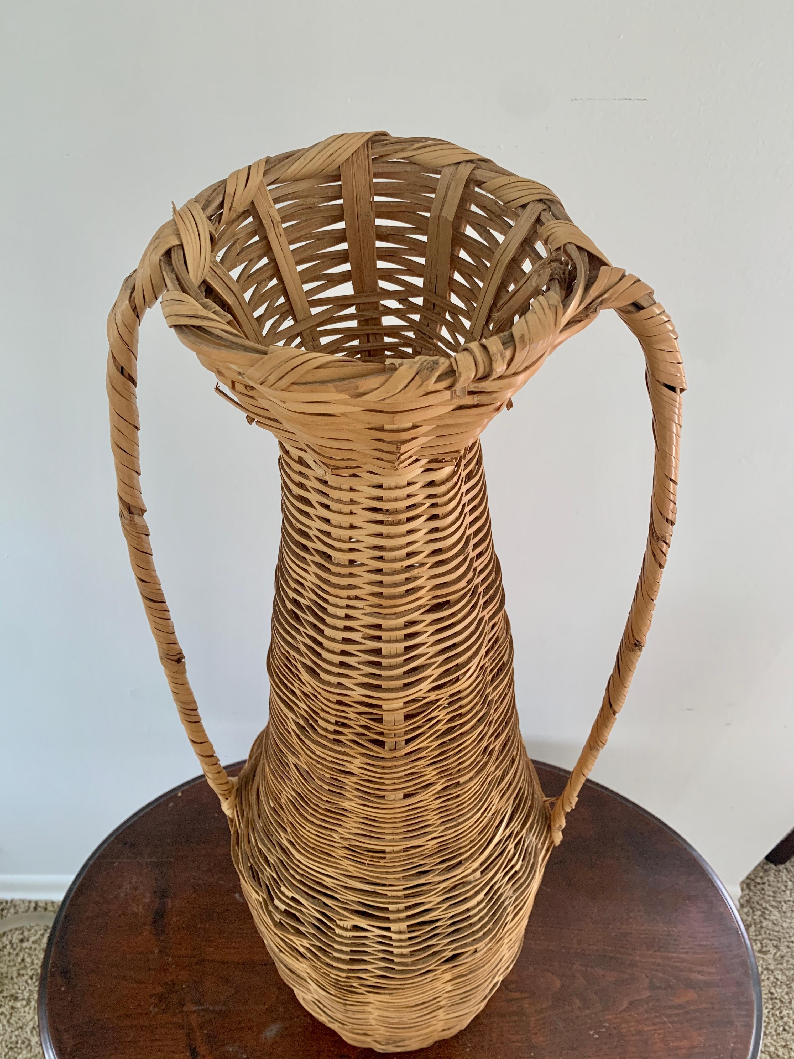 Un charmant vase panier de sol en osier tressé Boho Chic avec deux anses.

USA, Circa 1980

Dimensions : 12 