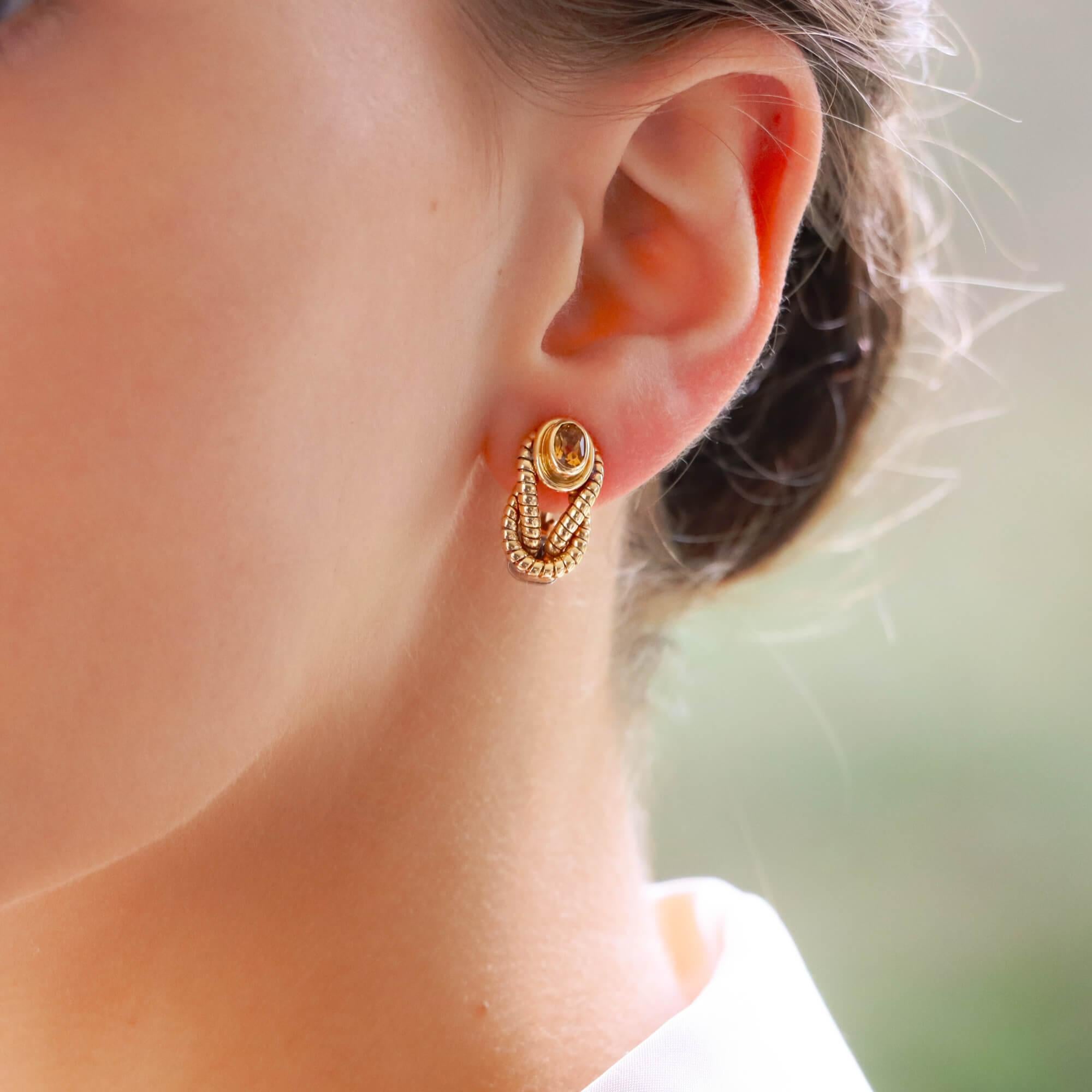 A fabulous pair of vintage Cartier ‘Hercules Knot’ citrine hoop earrings set in 18k yellow gold and stainless steel.

From the now discontinued 1980’s Hercules Knot collection, this pair predominantly feature a vibrant orange faceted oval citrine