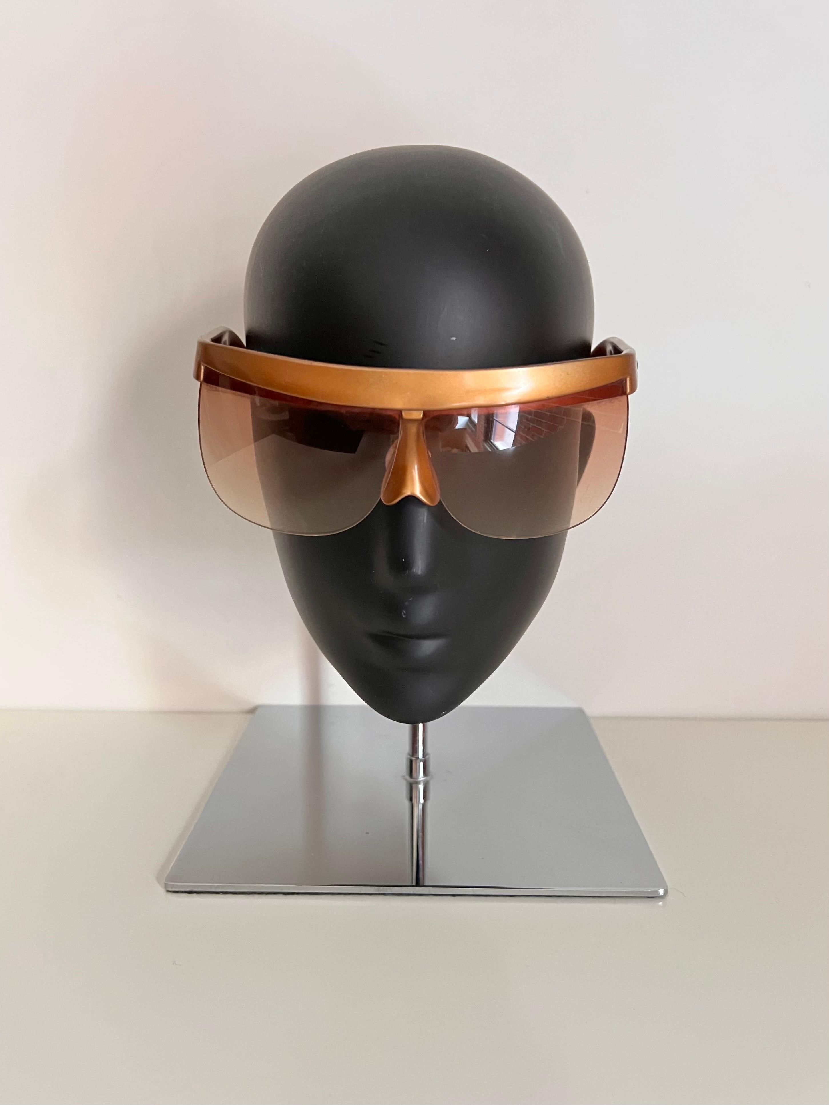 Avant garde, rare and unique Andre Courreges 7853 1980’s style sunglasses. Sleek gold futuristic mask frame holding a graduated tint pair of gold lenses.

One of a kind piece of eyewear history.

In very good vintage condition, does have some minor