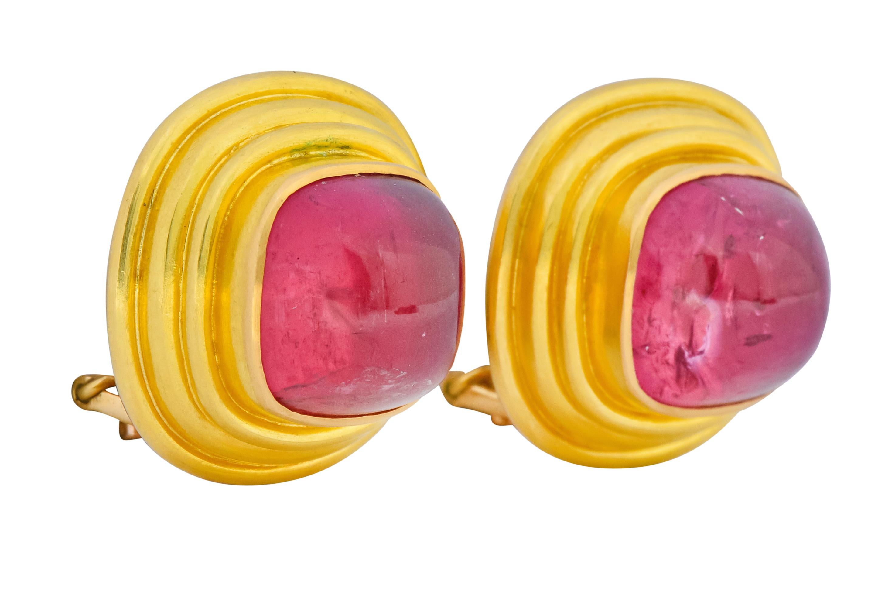 Each centering a highly domed cushion cabochon pink tourmaline, transparent and a saturated pink with beautiful natural inclusions

Bezel set in a matte gold surround with multiple ridges

Completed by a hinged omega back with optional articulated