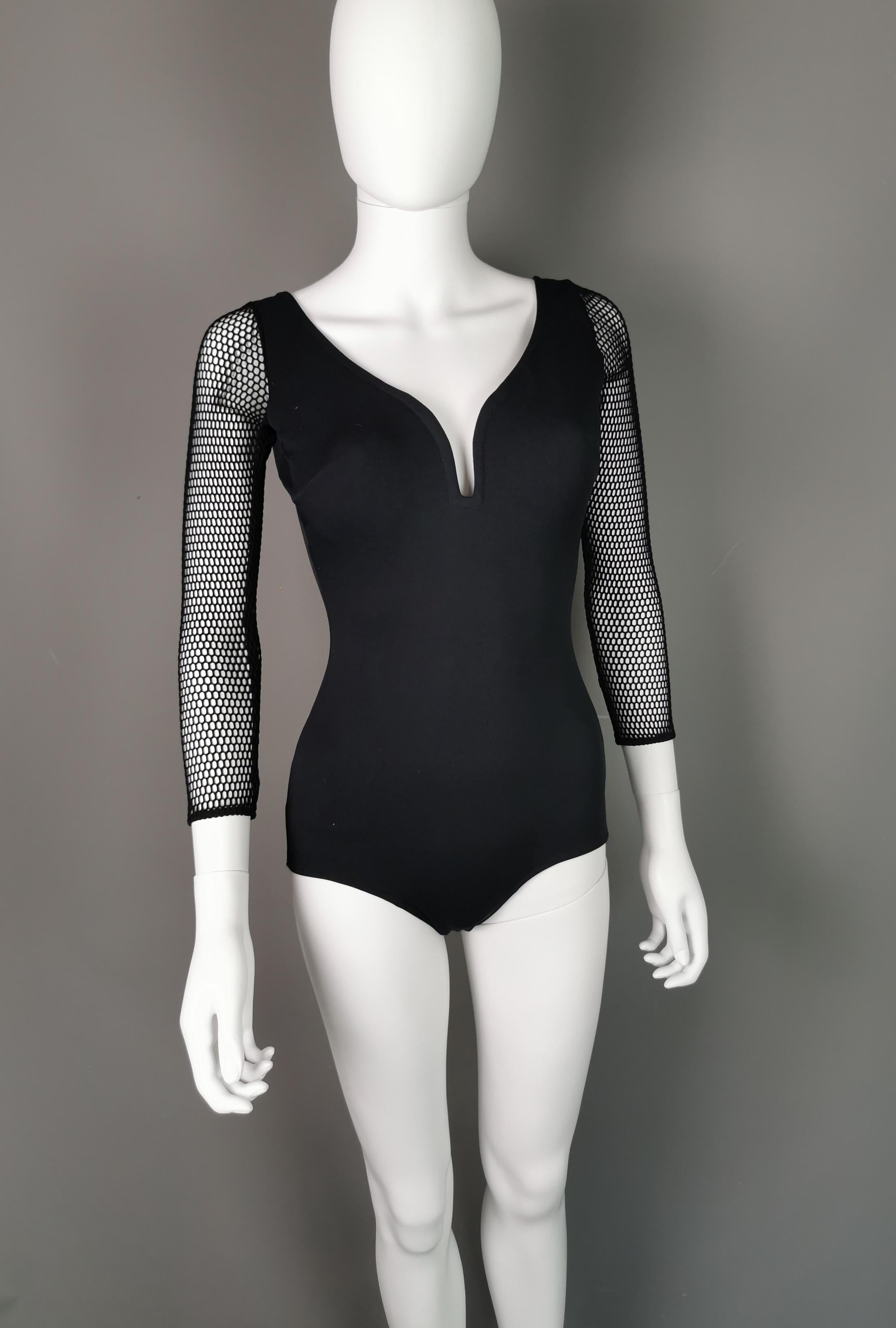 A gorgeous vampy 1980s original swimsuit.

It is in a rich sleek black stretchy fabric with a v neck, low cut back and with padded cups.

Perhaps the best thing about this sassy swimsuit is the amazing stretch fishnet sleeves.

This is an amazing