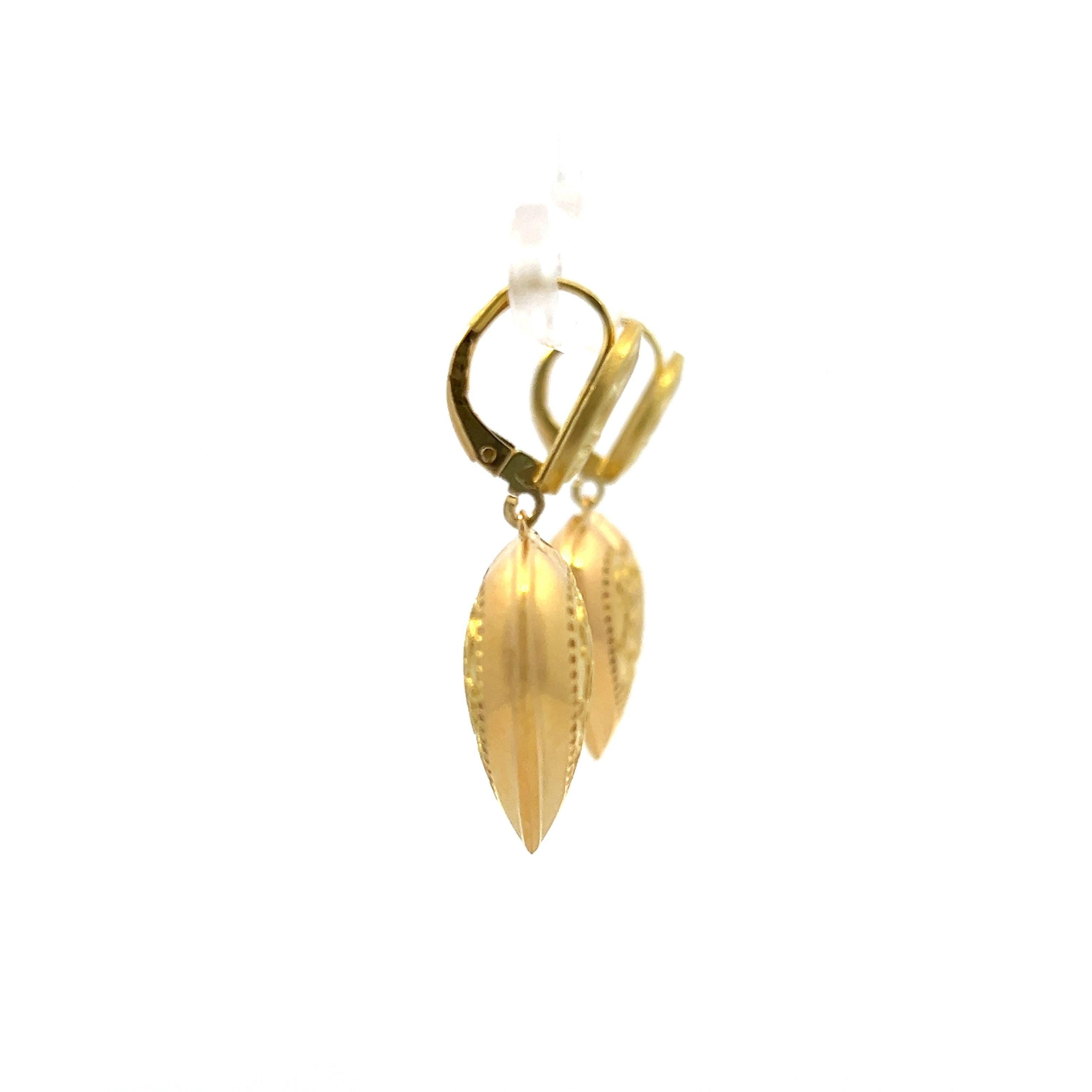 This charming pair of vintage 1980s drop earrings is crafted in rich 18 karat yellow gold and showcases a romantic heart-shaped design adorned with intricate floral motifs and a fleur-de-lis accent. The fleur-de-lis, a stylized lily, has long been a