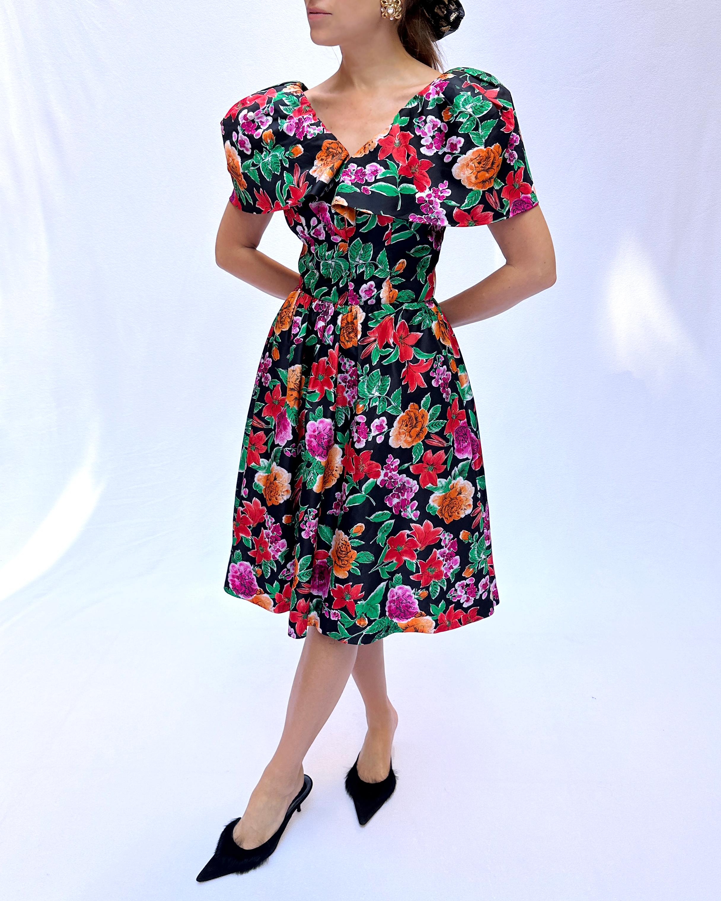 This vintage 1980s floral party dress is pure feminine fun. The black background on this floral print is my preferred way to wear florals in the cold-weather months. Classic 1980s puff shoulders take on a new shape with this cape neckline, bolstered