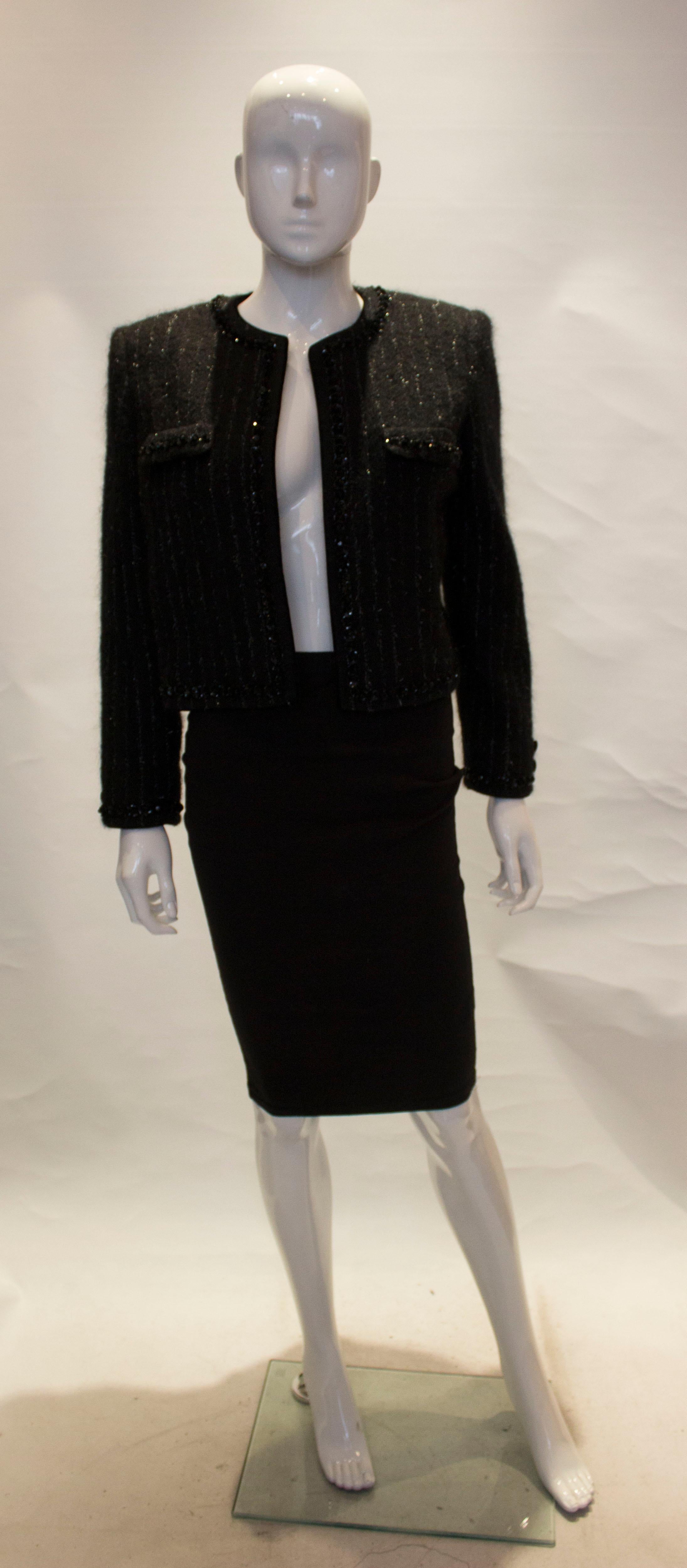 A beautiful vintage jacket by Giorgio Grati. n a black wool mix with a silver vertical stripe, the jacket is collarless and two faux flap pockets. It has a bead detail along the edge and pockets.