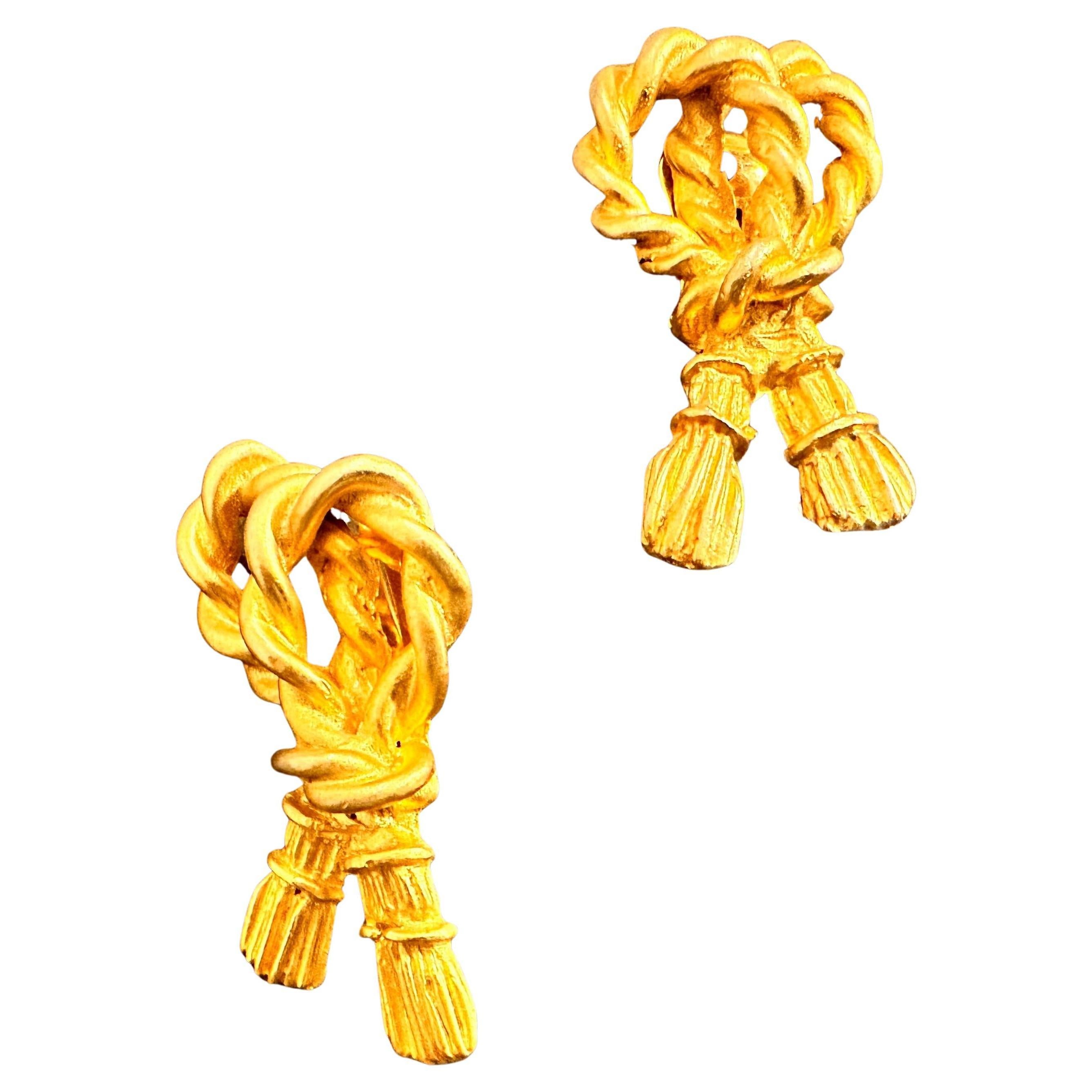 These vintage 1980s earrings are crafted in a luxurious gold-tone metal, featuring an elegant and eye-catching design that captures the bold spirit of the era. The earrings display a distinctive twisted-rope motif, where the metal is intricately