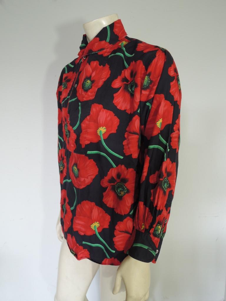 Vintage KENZO pullover shirt with a vibrant poppy print. If worn unbuttoned, presents similar to a shawl collar. Black base with red, green and yellow flowers. Features orange, green black and beige. Made in Japan, 100% cotton. In good vintage