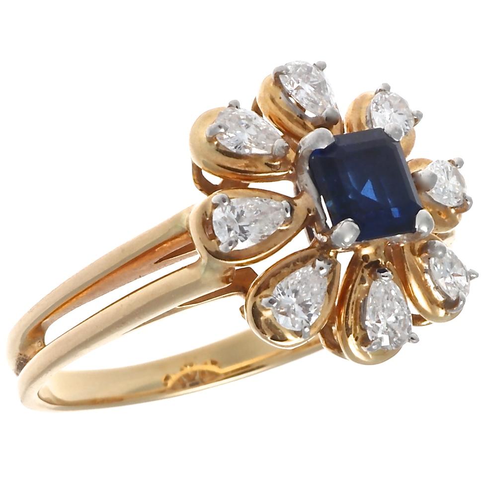 A beautiful sapphire and diamond flower, set in 18 karat gold, from the iconic jewelry house of Oscar Heyman Brothers. Featuring an emerald cut sapphire that weighs approximately 0.70 carats. With eight pear shaped diamonds that weigh approximately