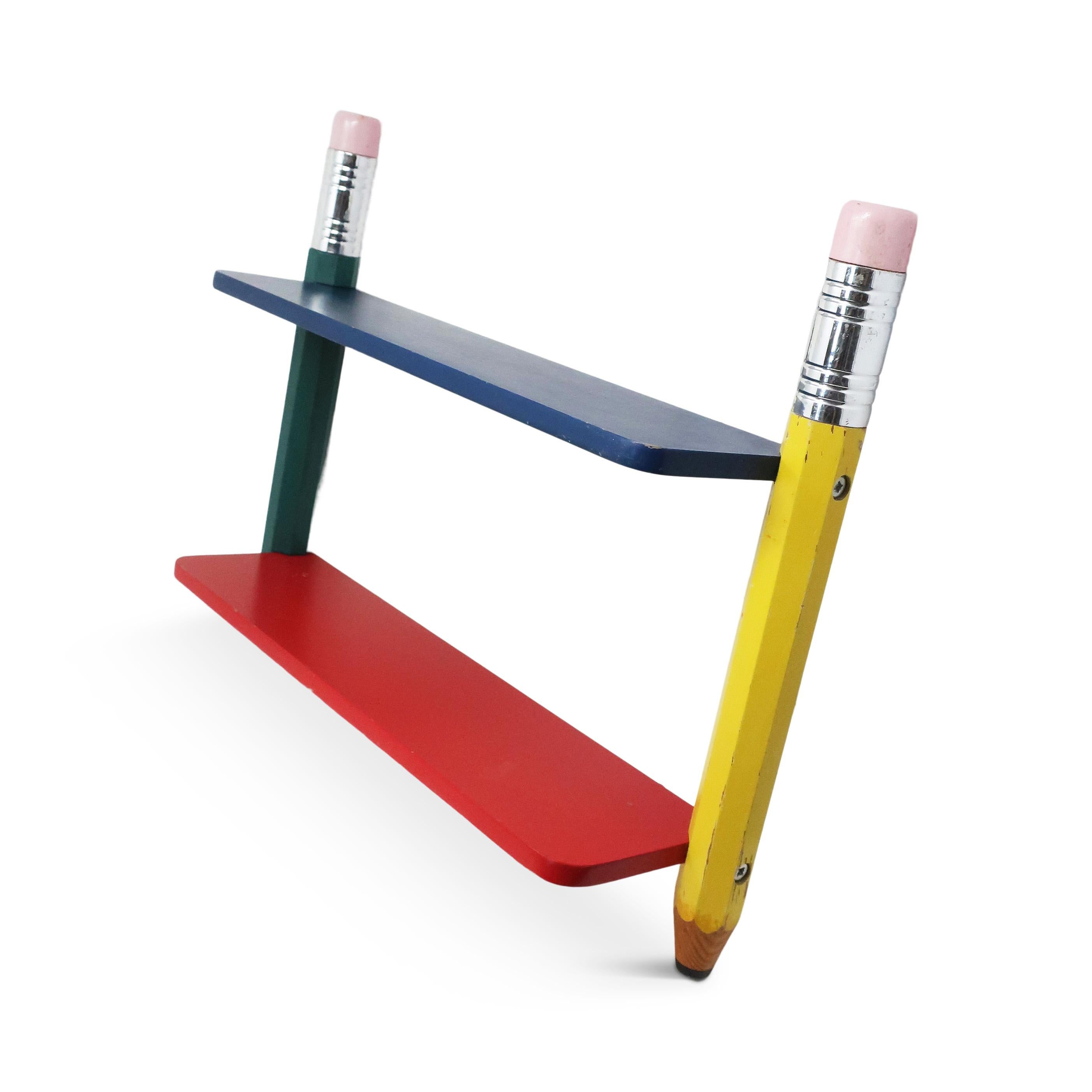 A great piece from Pierre Sala’s postmodern pencil themed children’s furniture from the 1980s for Pierre Sala Furniture. Design is composed of two shelves, one blue and red, supported by two pencils, one yellow and one green. Includes rings on rear